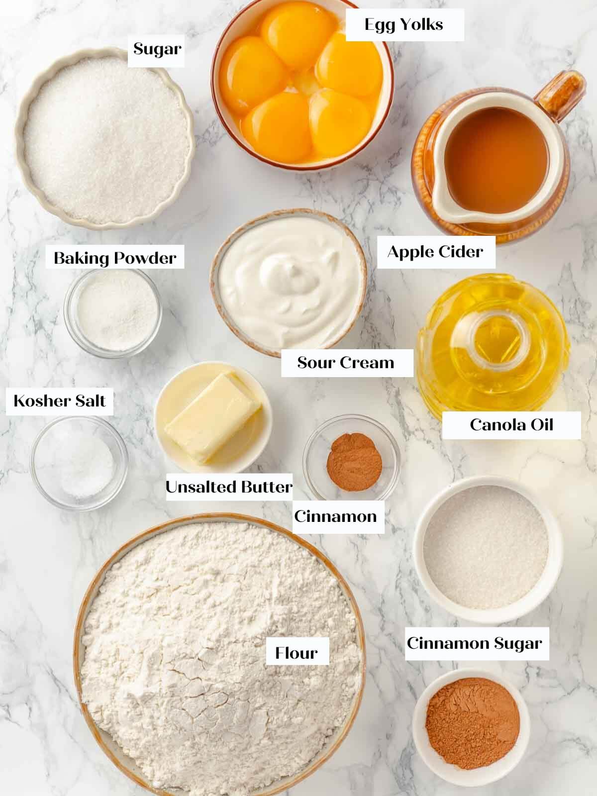 Ingredients for apple cider donuts laid out on a white marble countertop.