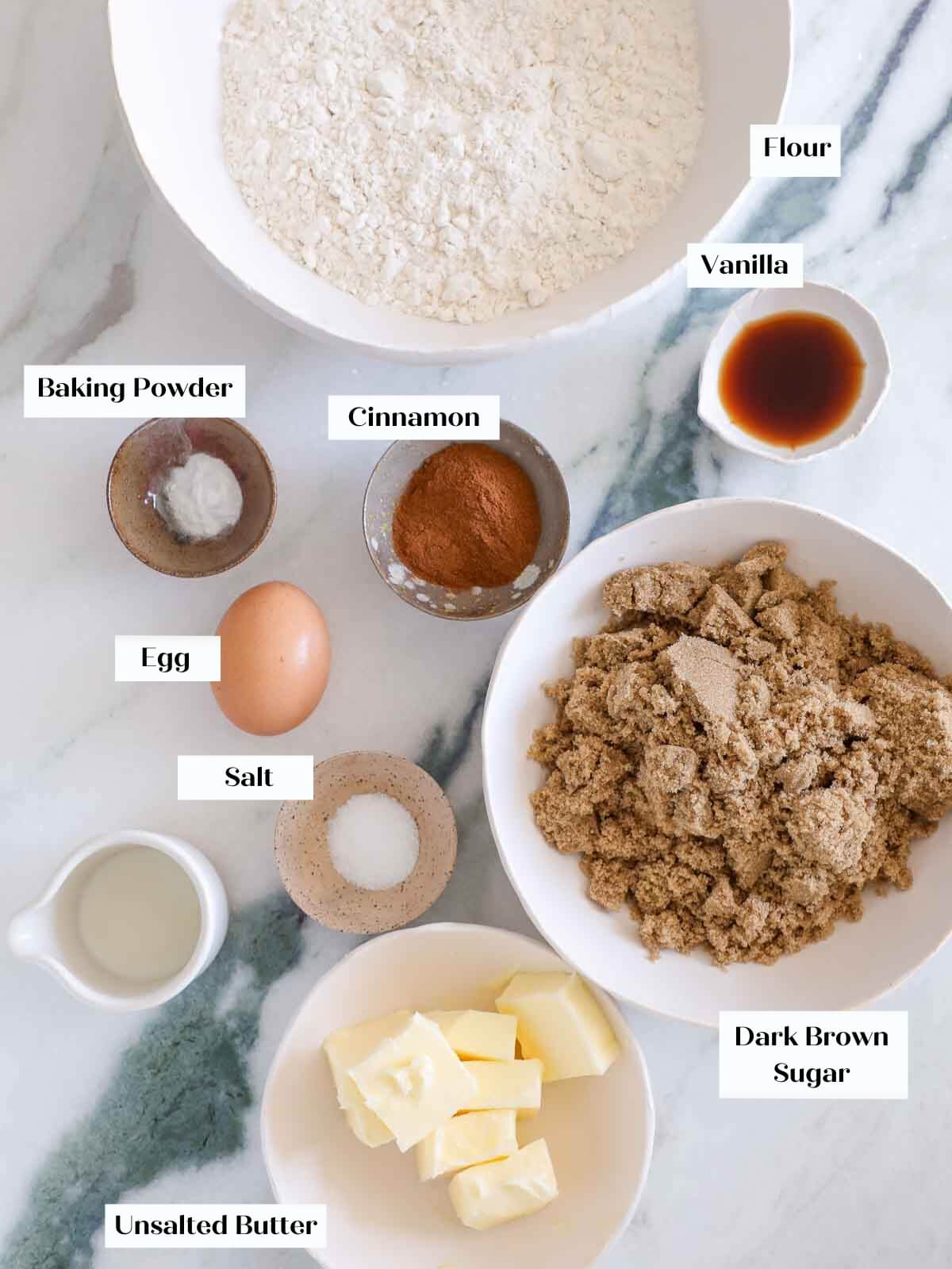 Ingredients for cinnamon sugar cookies laid out on a white marble surface.