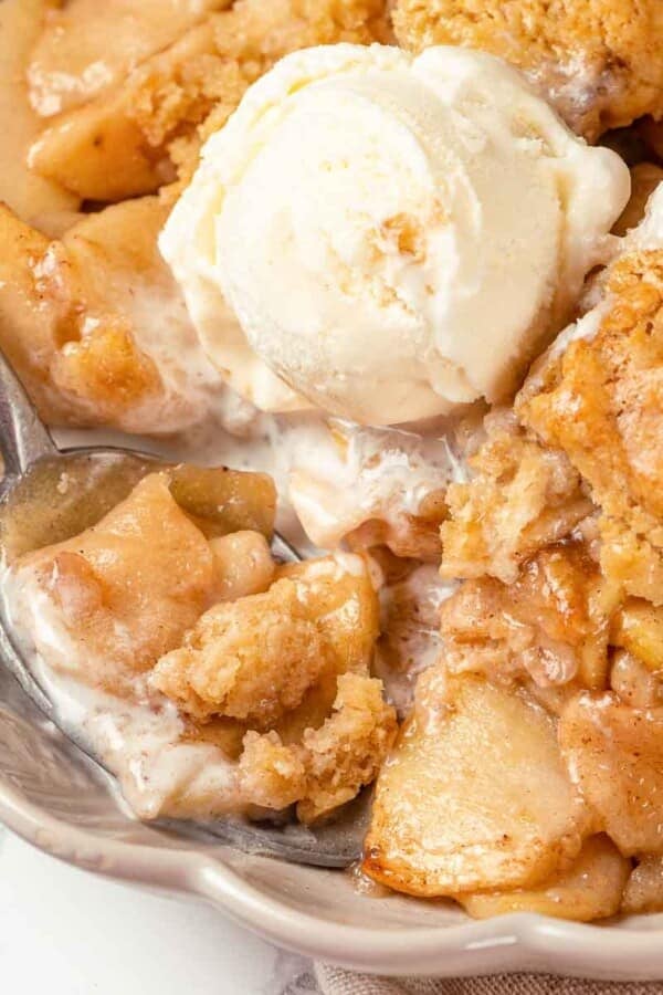 A scoop of vanilla ice cream melting on warm apple cobbler.