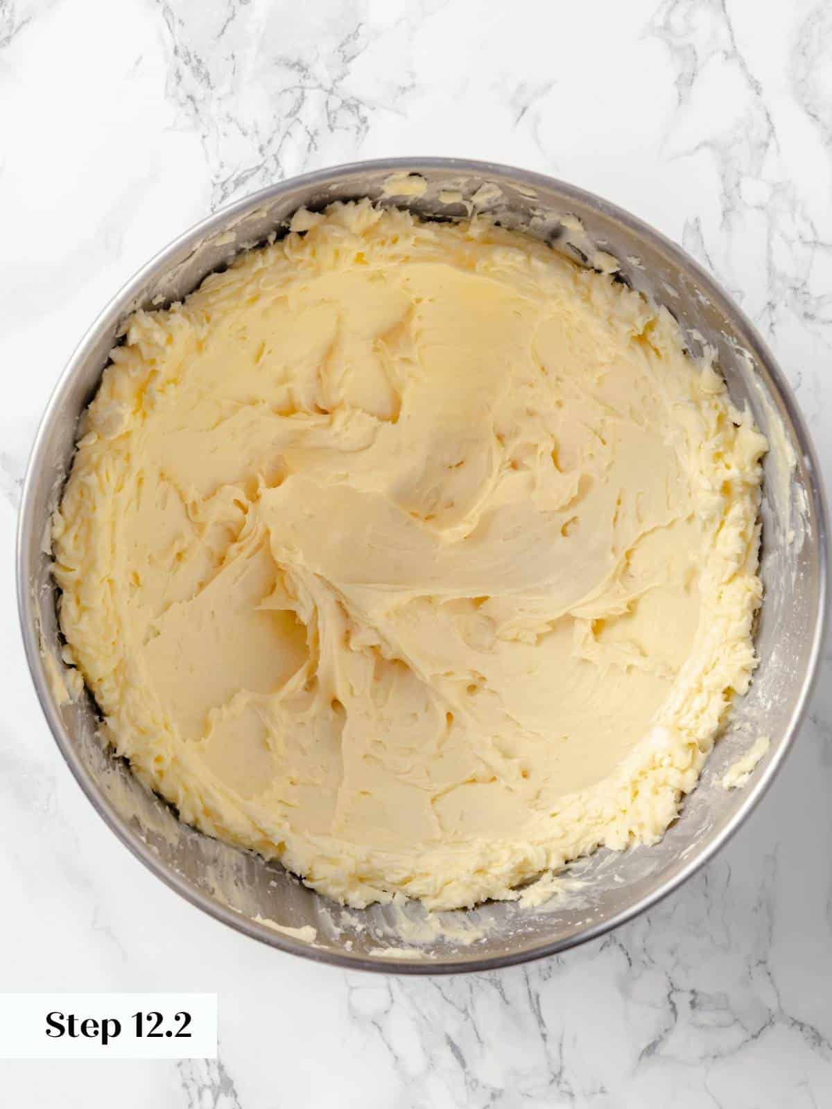 Frosting for the applesauce cake in a metal mixing bowl.