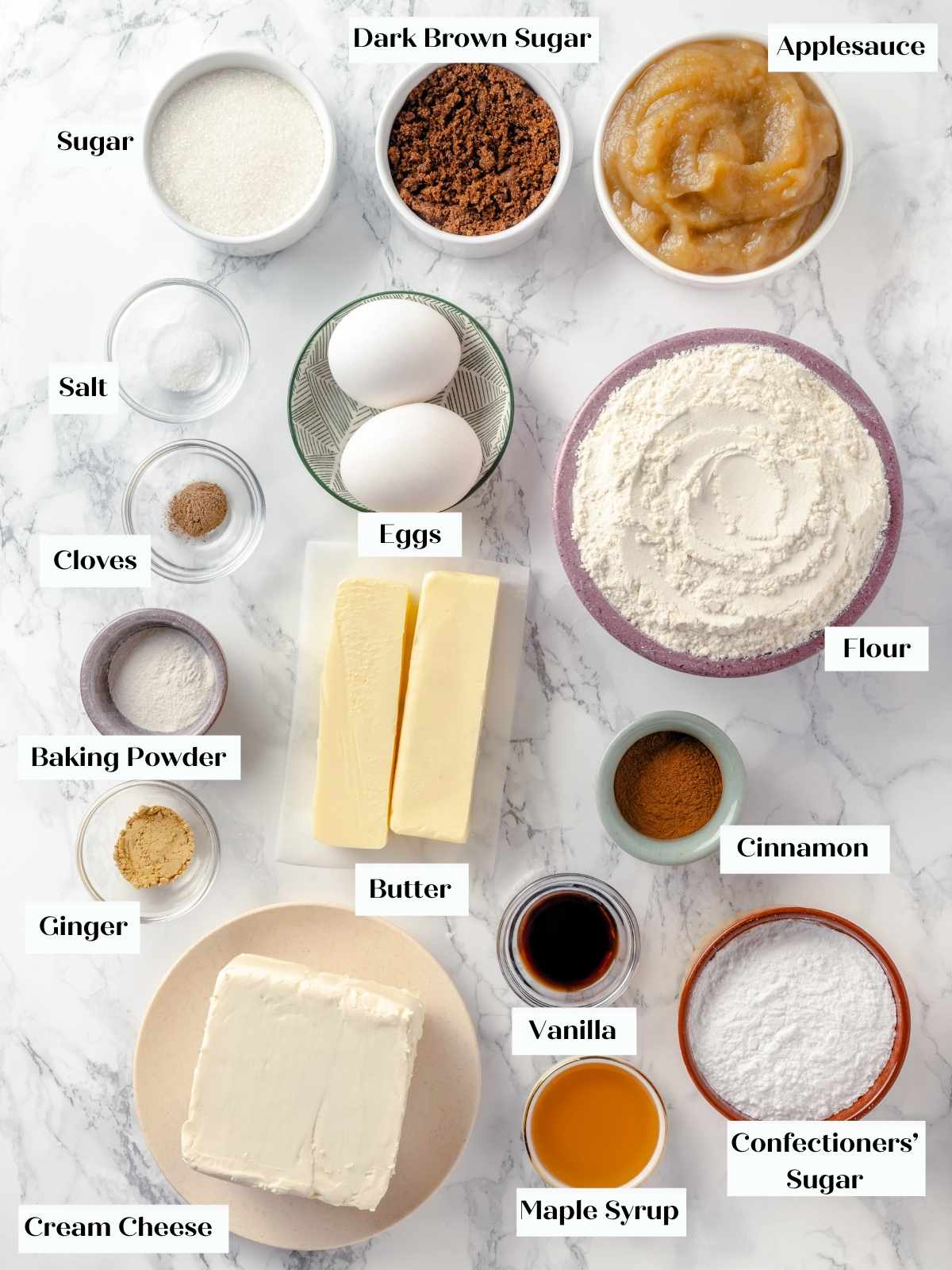 Ingredients for applesauce cake arranged on a white marble countertop.