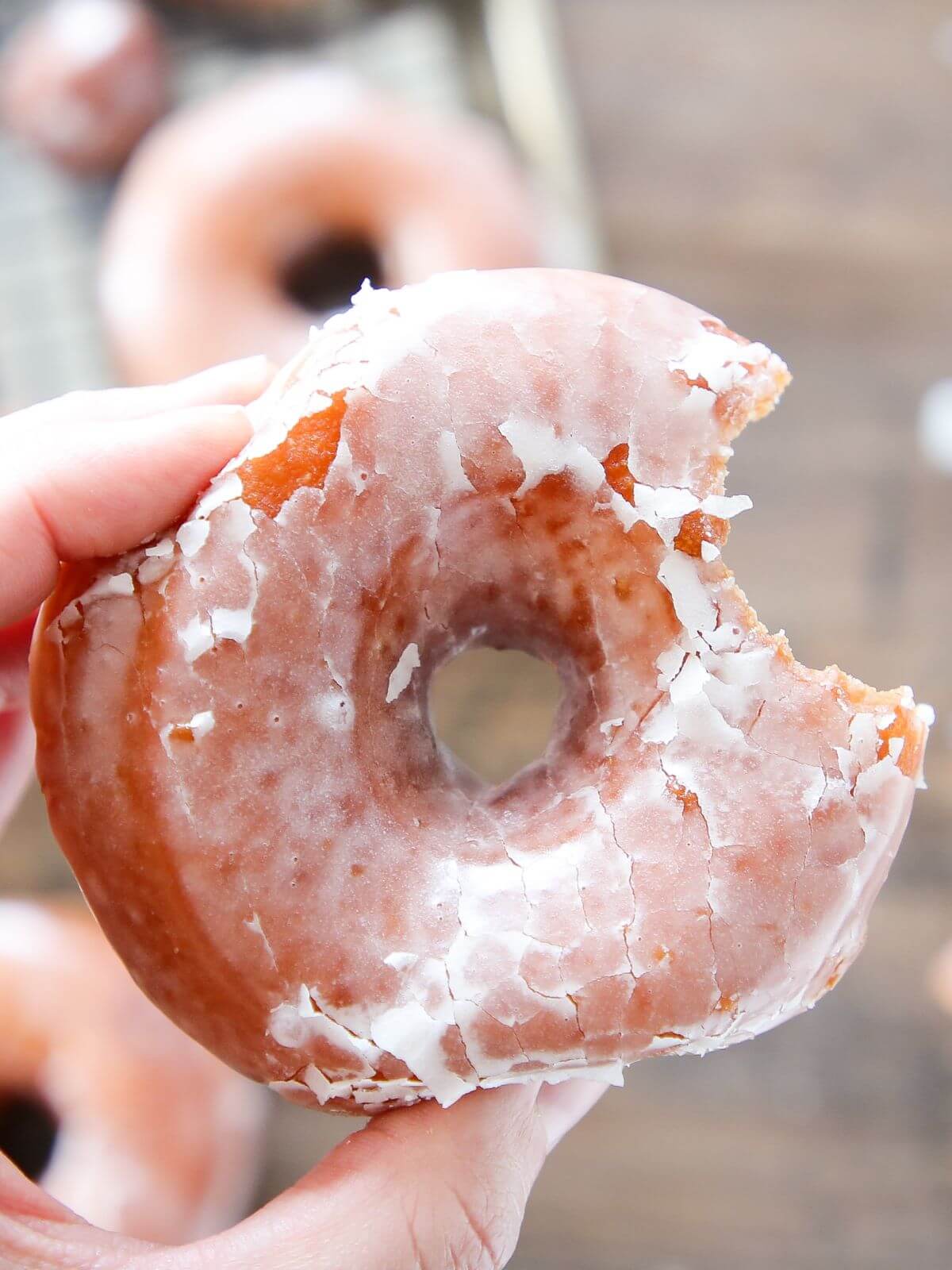 A hand holding a Krispy Kreme donut, ready to be enjoyed.