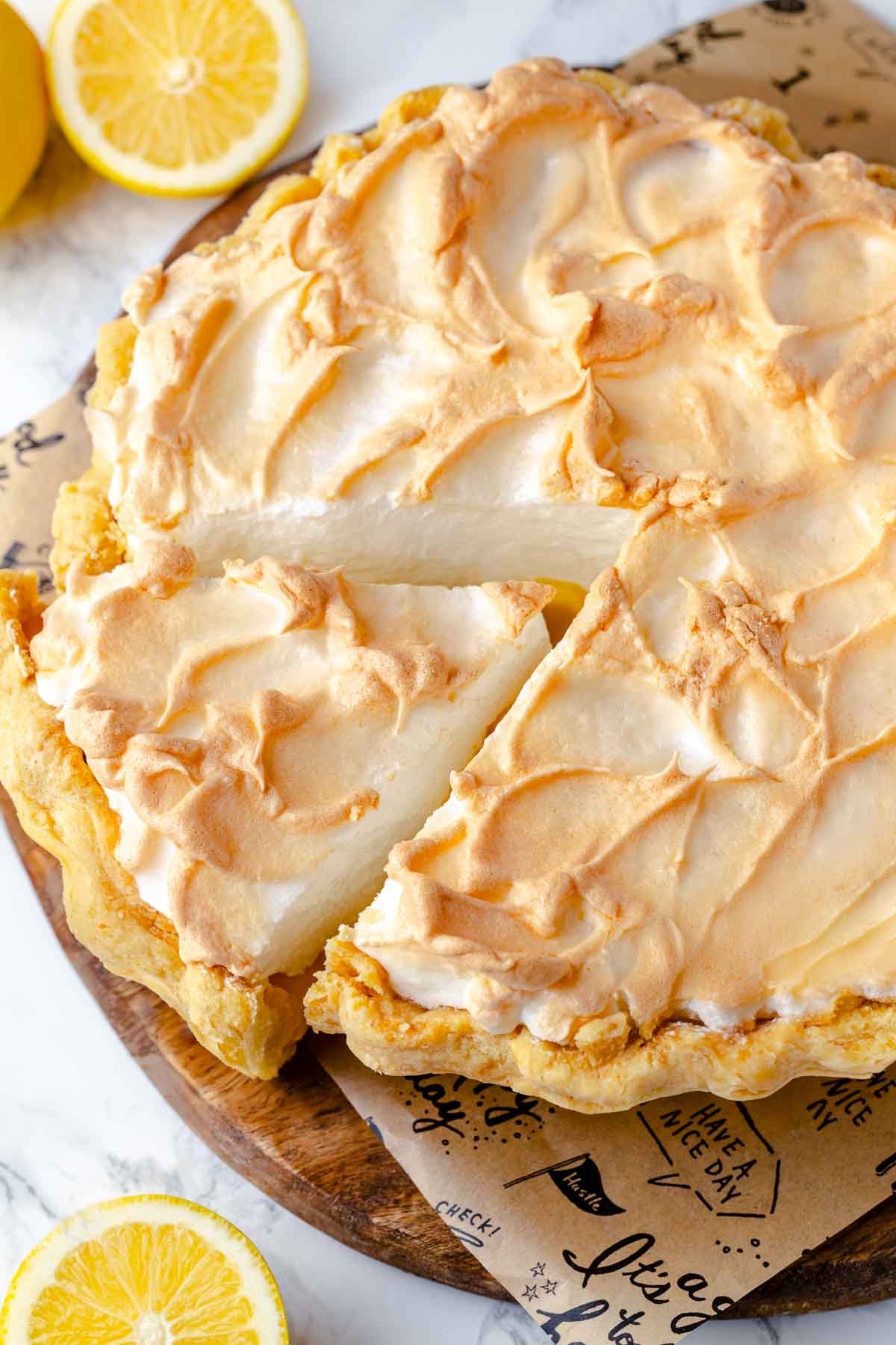 A fresh lemon meringue pie with whole lemons artistically arranged in the background.