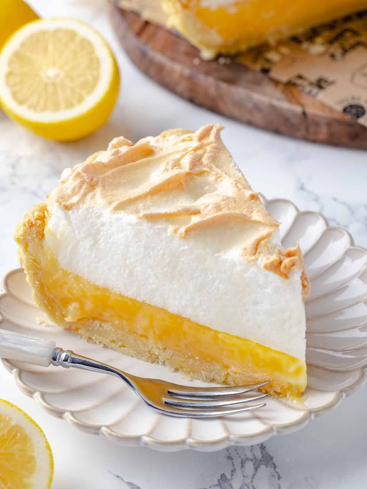 A slice of lemon meringue pie beautifully presented on a simple white plate.