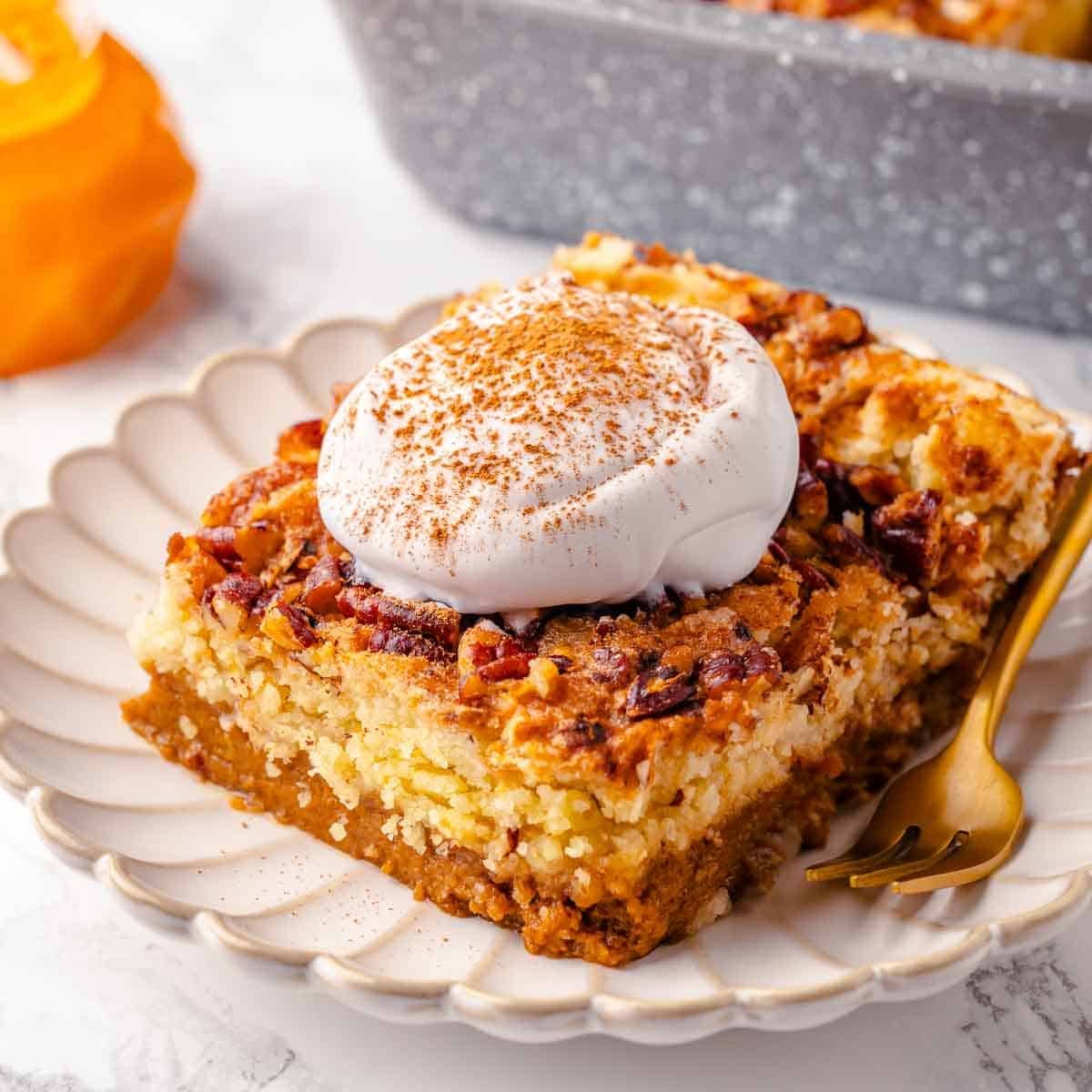 Pumpkin dump cake topped with a dollop of whipped cream on a plate, ready to be served.