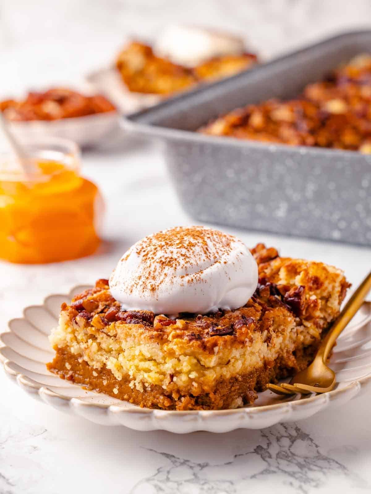 A slice of pumpkin dump cake on a plate with visible layers and a golden topping.