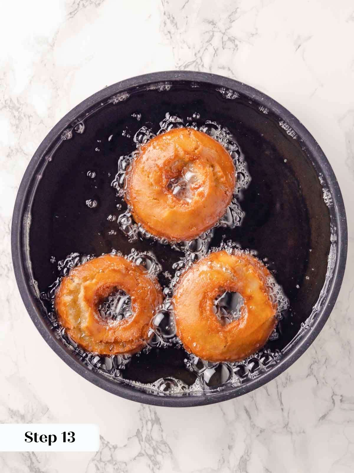 Apple cider donuts frying in hot oil, achieving a golden brown color.