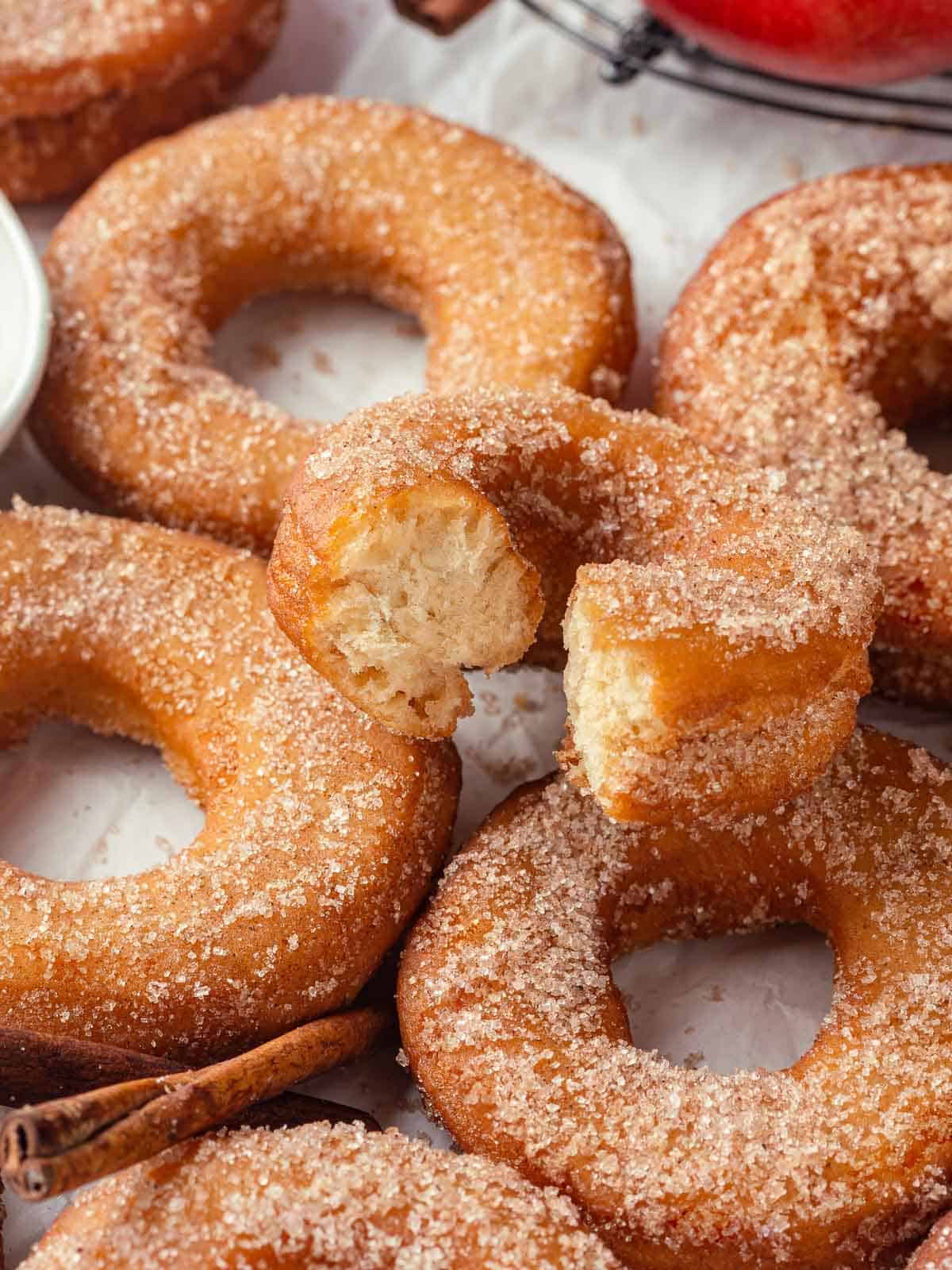 A group of apple cider donuts resting on a countertop, highlighting their warm, sugared coating.