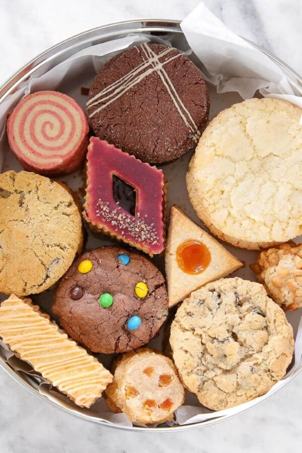 An open tin of assorted cookies, with different shapes and flavors displayed.