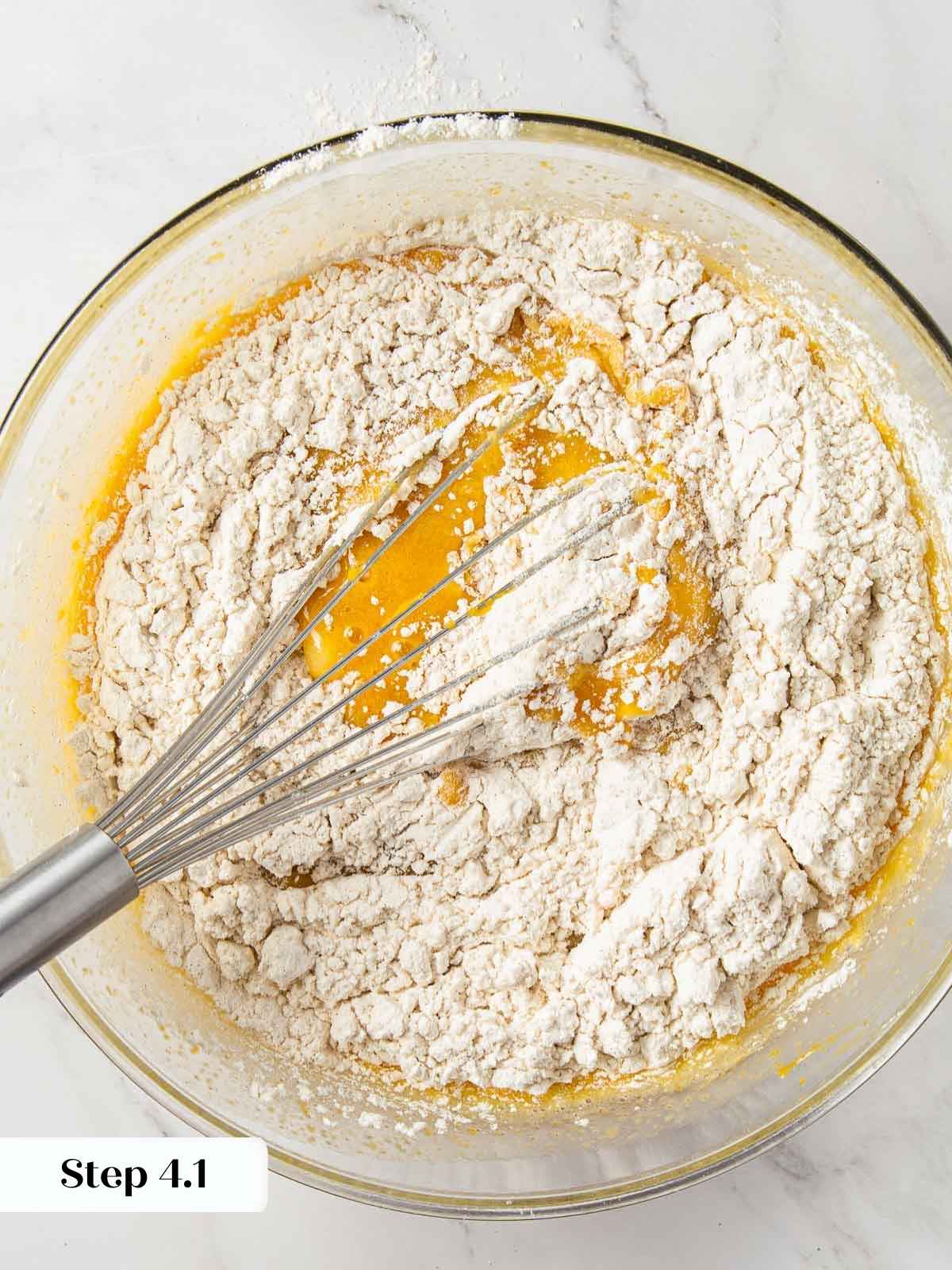 Wet and dry ingredients for pumpkin bread being mixed together.