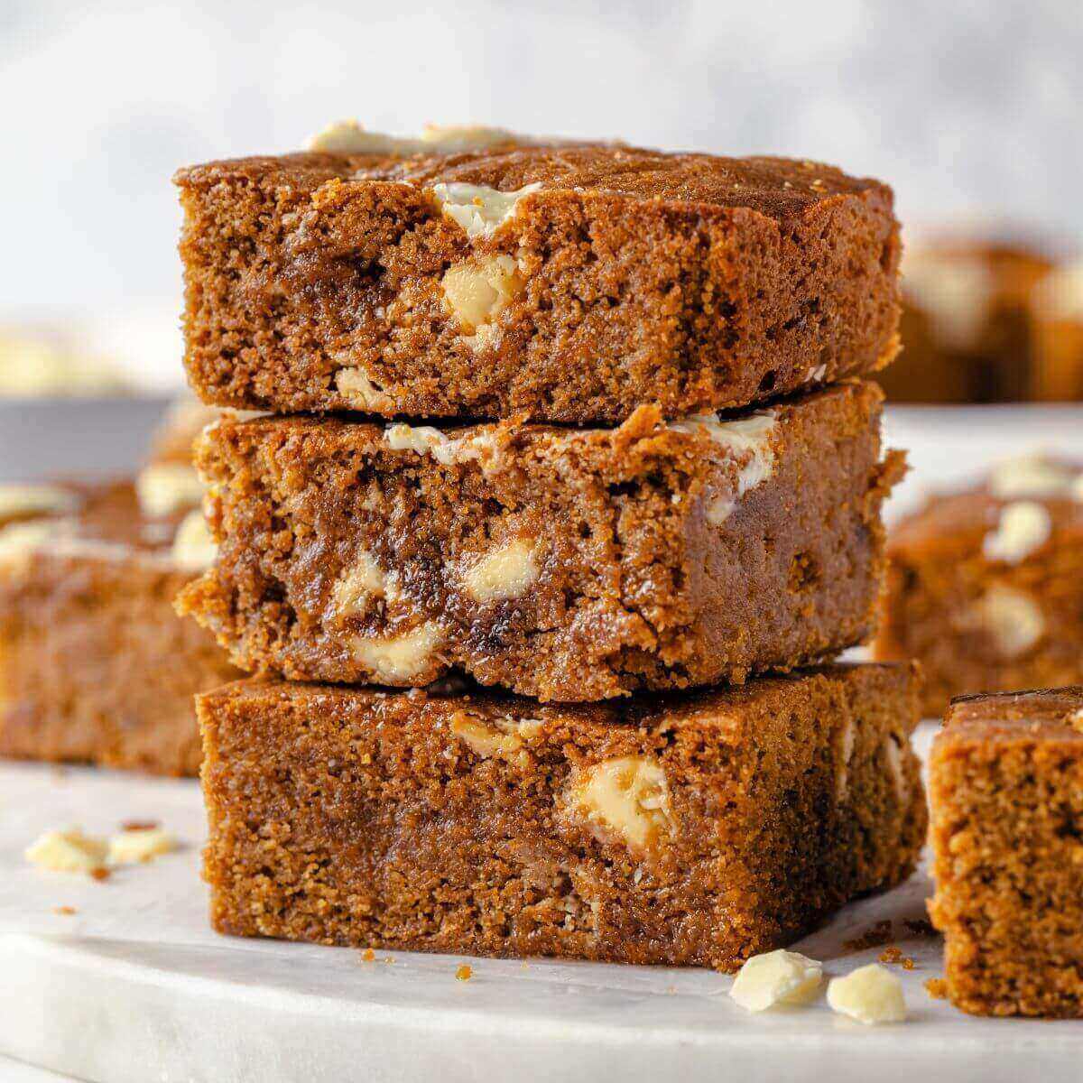 A stack of three gingerbread blondies, showing their chewy texture and soft interior.