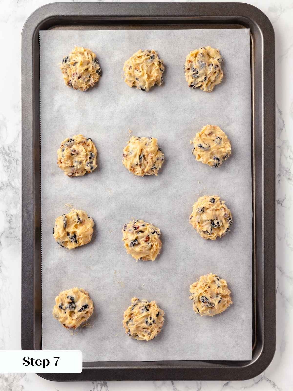 Dollops of hermit cookie batter placed evenly on a lined baking sheet.