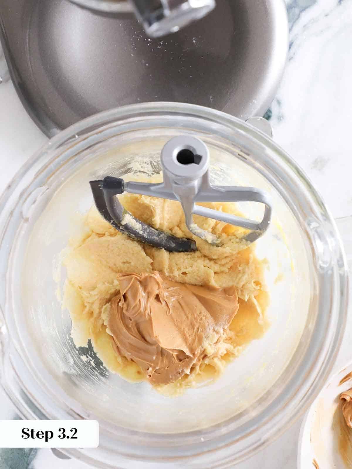 A spoonful of creamy peanut butter being added to a mixing bowl for monster cookie dough.