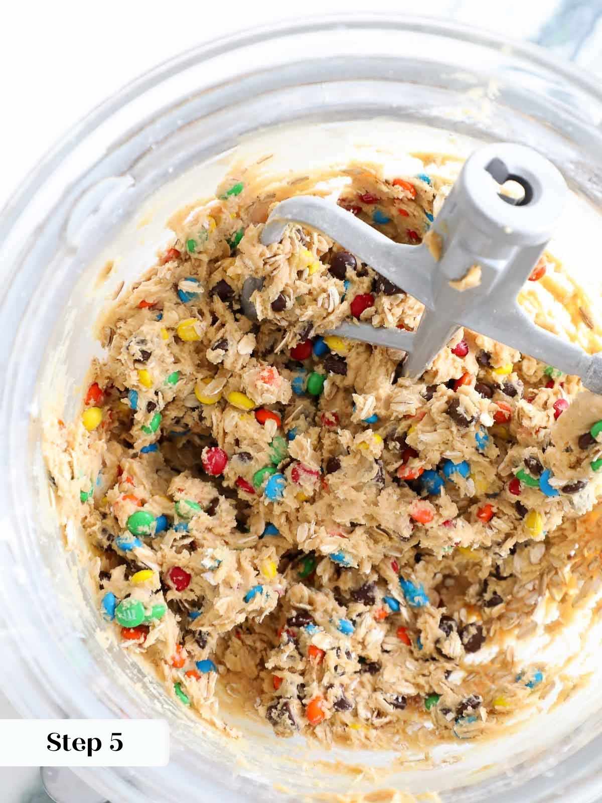 A clear mixing bowl filled with chunky monster cookie dough packed with mix-ins.