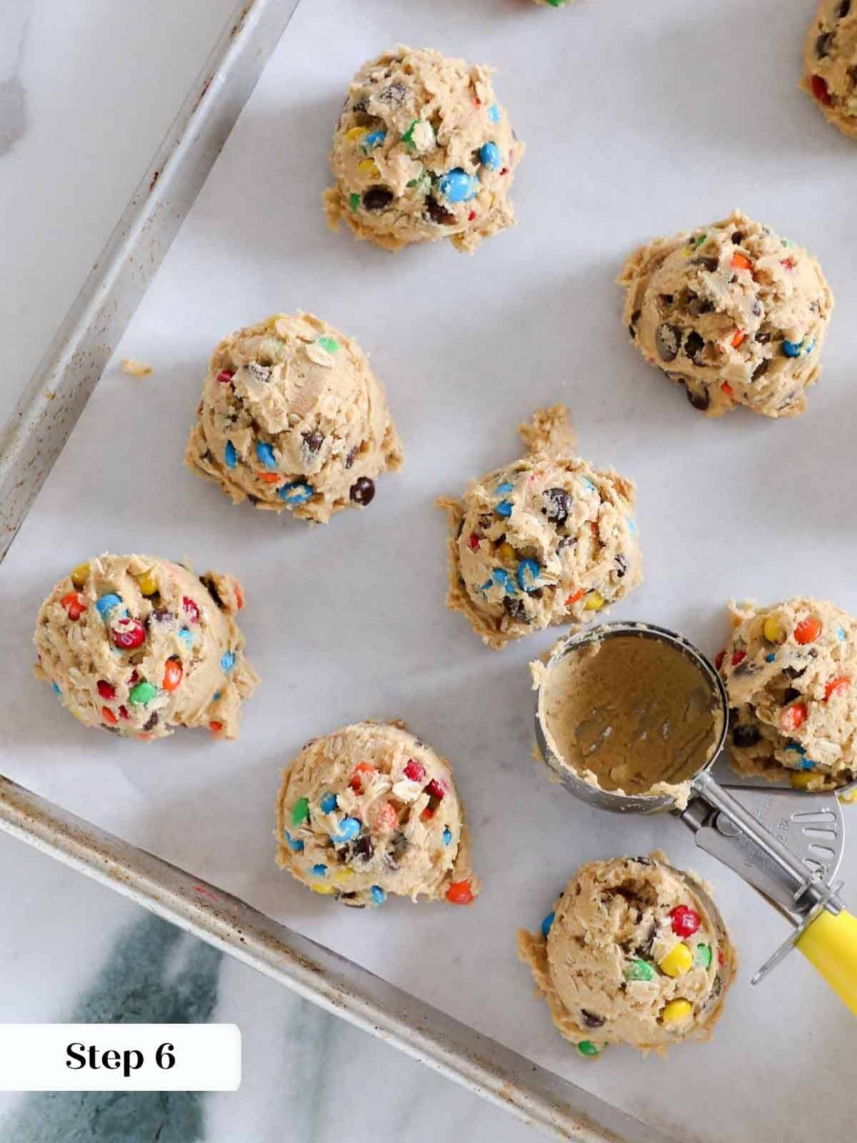 Scooped portions of monster cookie dough placed evenly on a baking sheet.