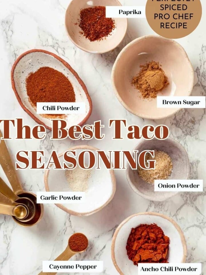 Taco seasoning in a bowl with a spoon, surrounded by chili powder and cumin.