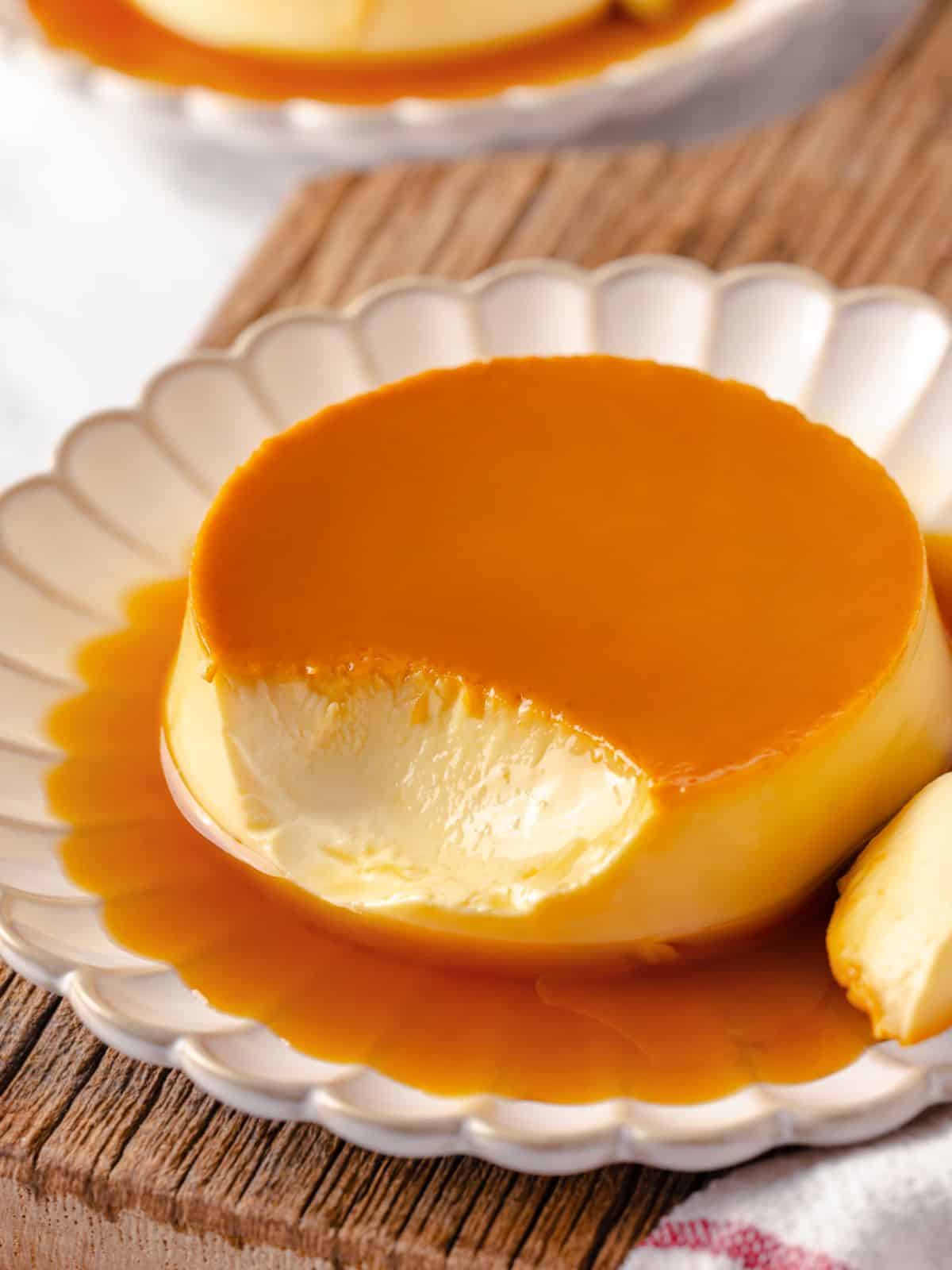 A creme caramel dessert with a bite taken out, revealing its creamy, smooth texture.