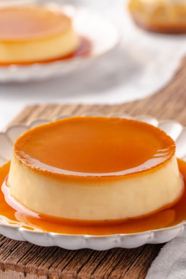 A single portion of creme caramel with a glossy amber caramel top served on a white plate.