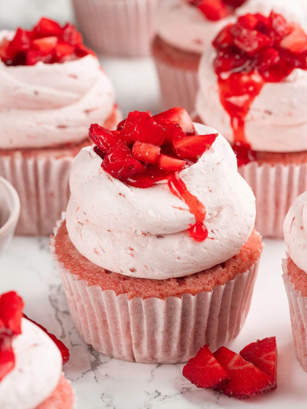 Frosted strawberry cupcakes with swirls of buttercream and a fresh strawberry garnish.