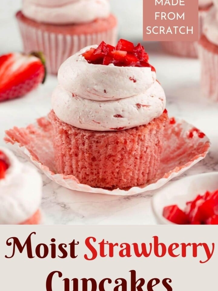 Close-up shot of a moist strawberry cupcake with a swirl of buttercream frosting and a juicy strawberry garnish.