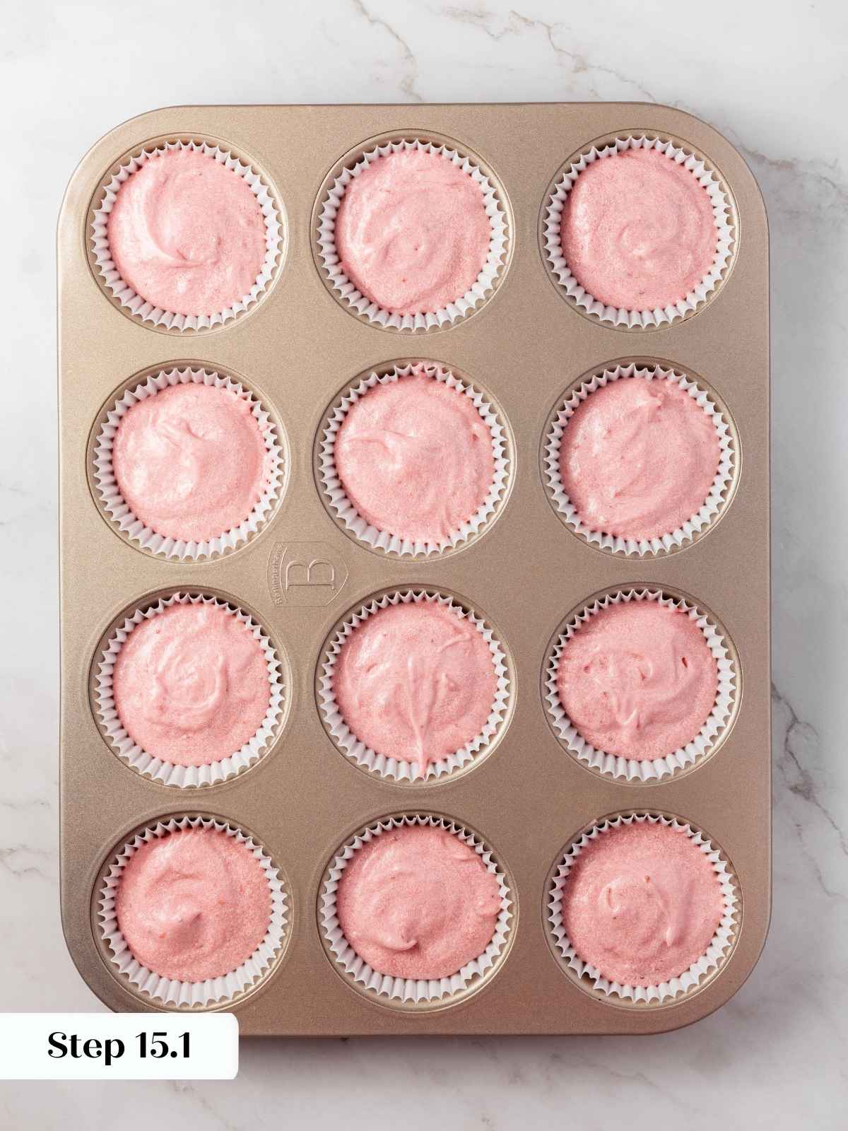 Strawberry cupcake batter portioned into a lined cupcake tin, ready to bake.