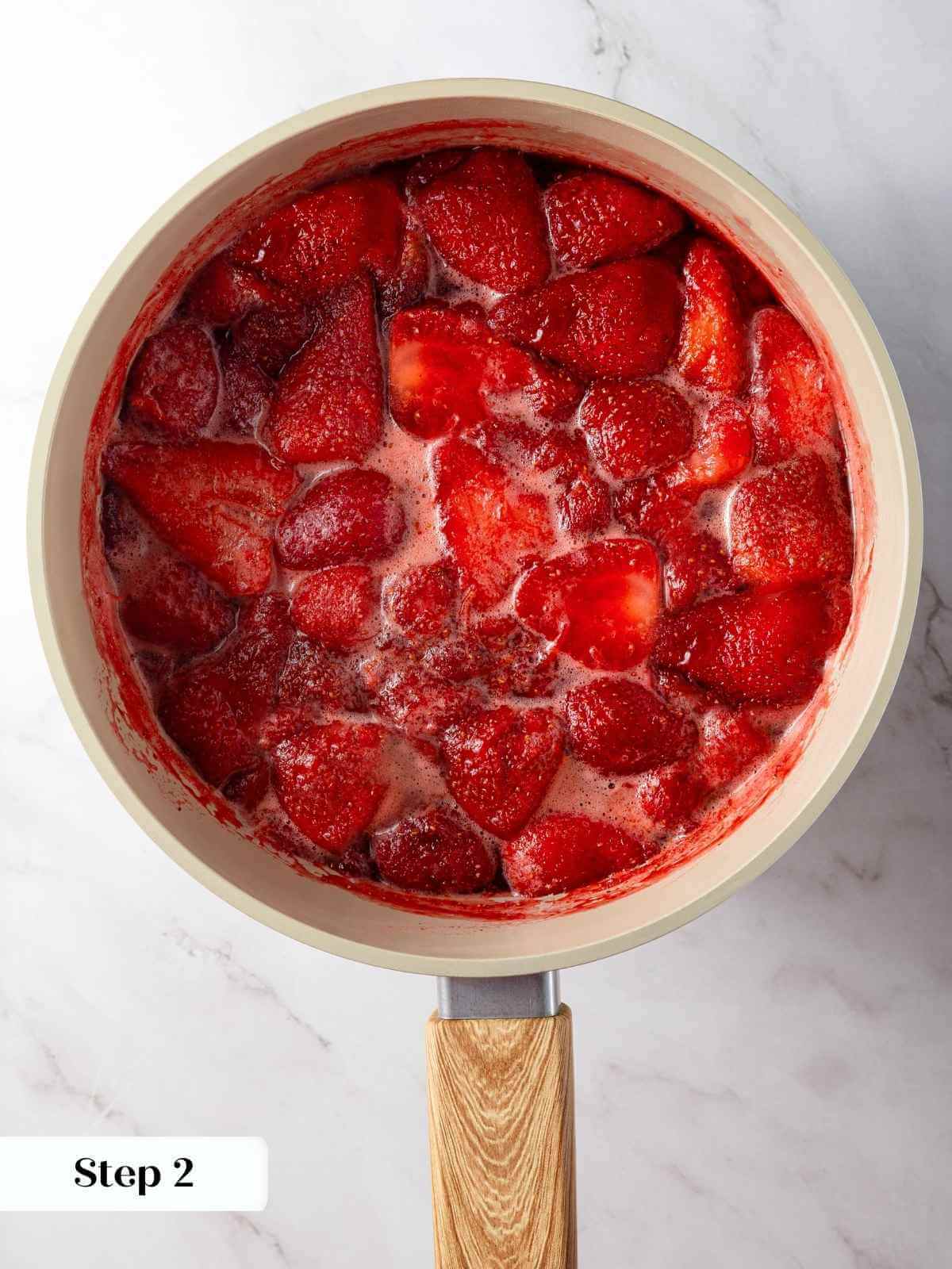 Strawberry jam mixture boiling in a saucepan to thicken and intensify the flavors.