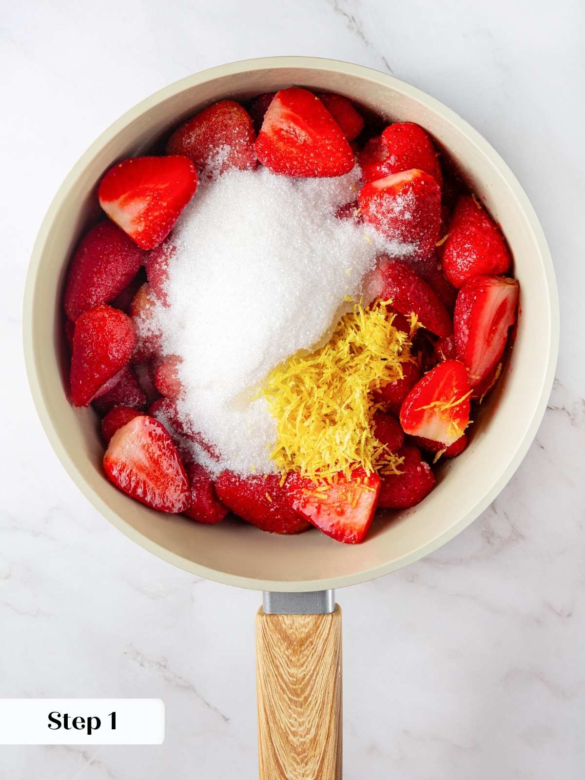 A saucepan filled with fresh strawberries, sugar, and lemon juice for making jam.