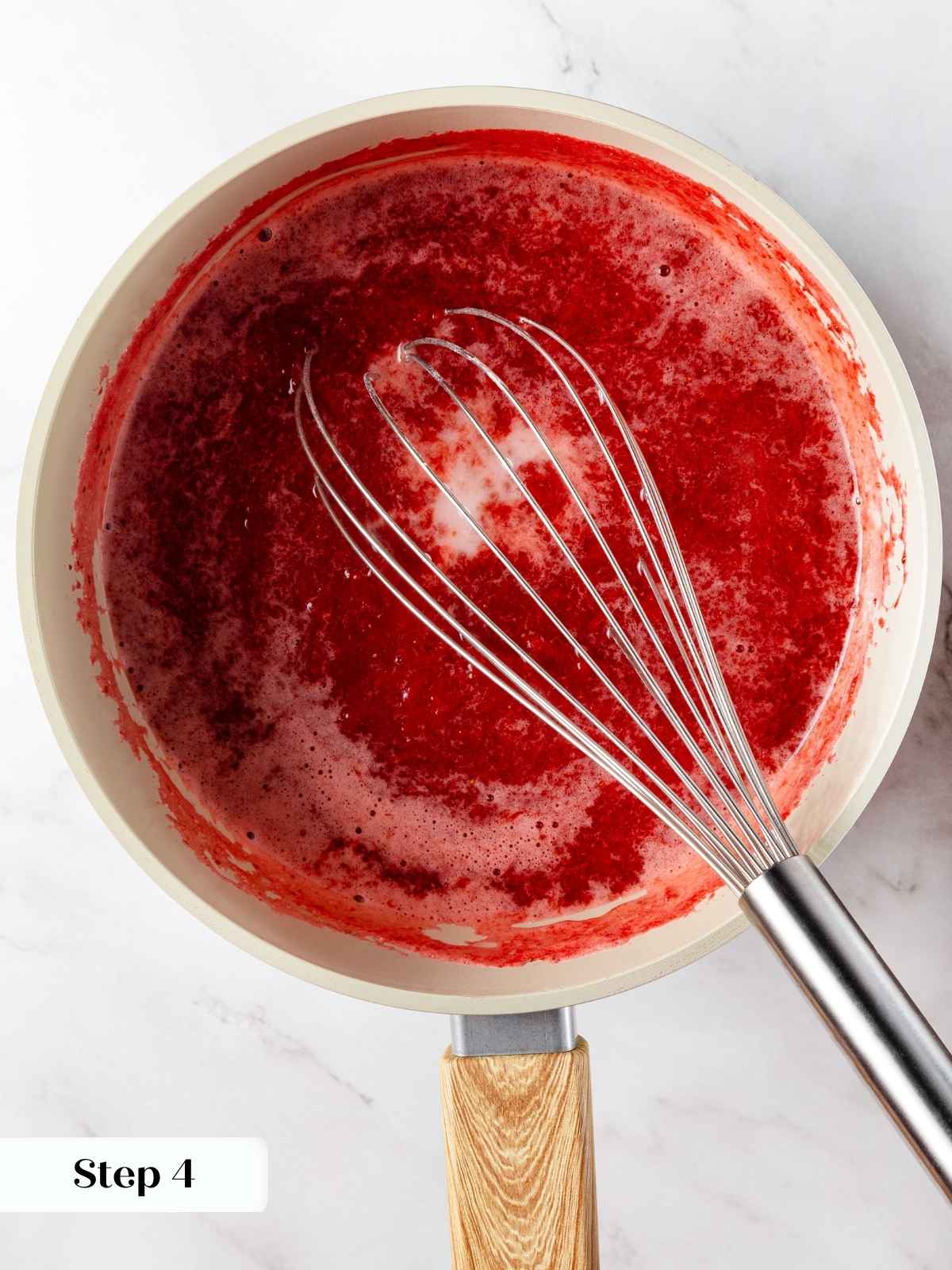 Cornstarch being whisked into a homemade strawberry jam mixture for thickening.