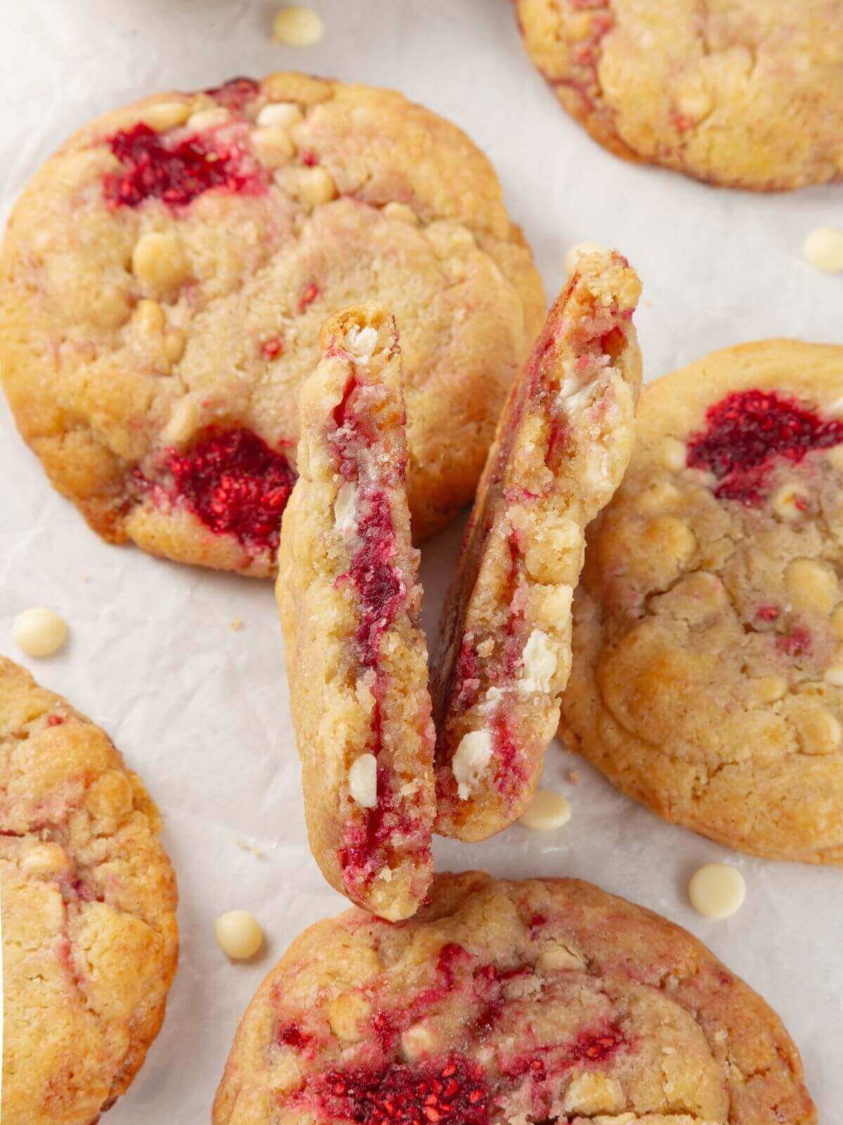 A close-up of a white chocolate raspberry cookie with a chewy, soft interior and melted chocolate.