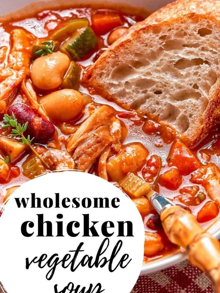 A comforting bowl of chicken vegetable soup on a rustic wooden table.