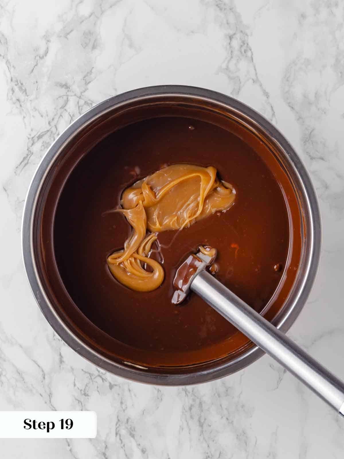 adding salted caramel sauce to hot ganache for frosting.