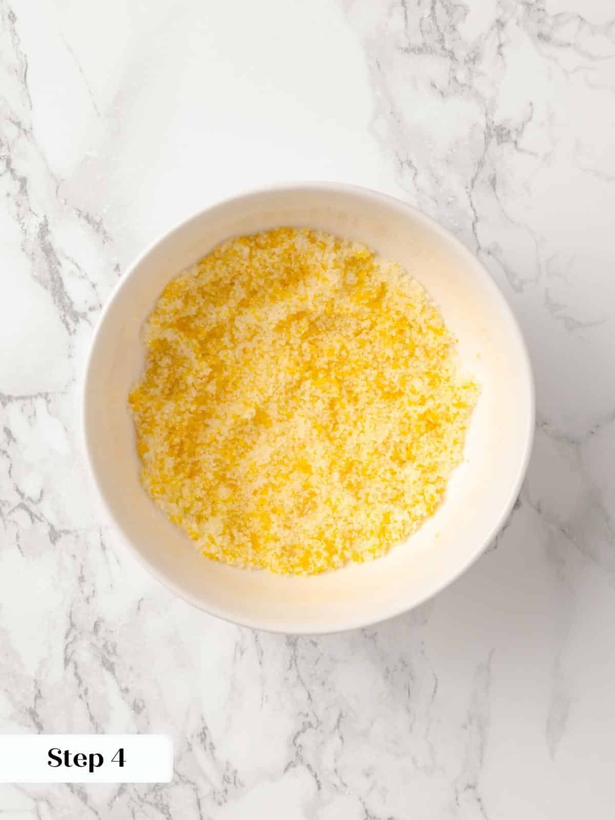 A small bowl of sugar and orange zest being combined.