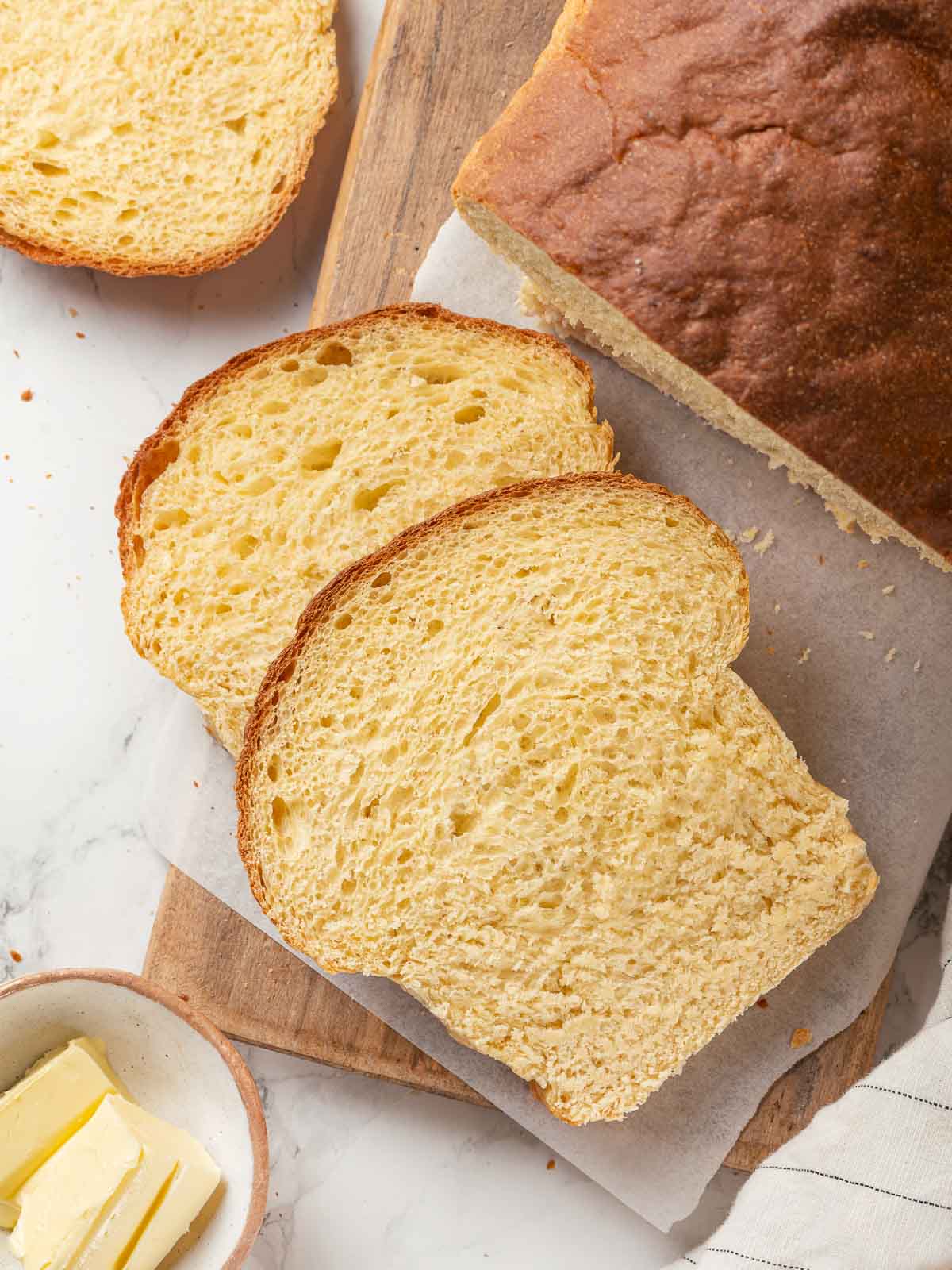 A loaf of potato bread sliced on a wooden cutting board.