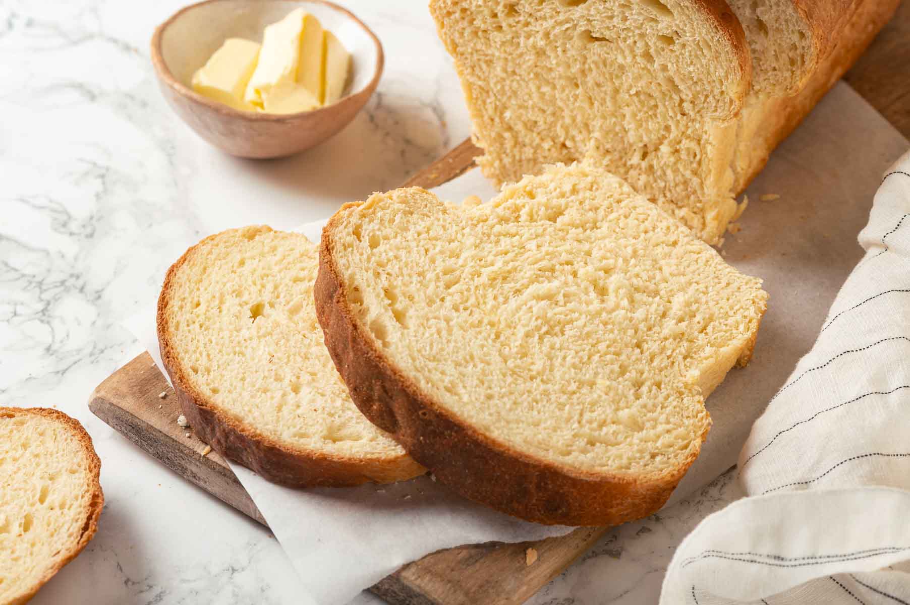 Freshly baked bread with a butter dish beside it, perfect for serving.