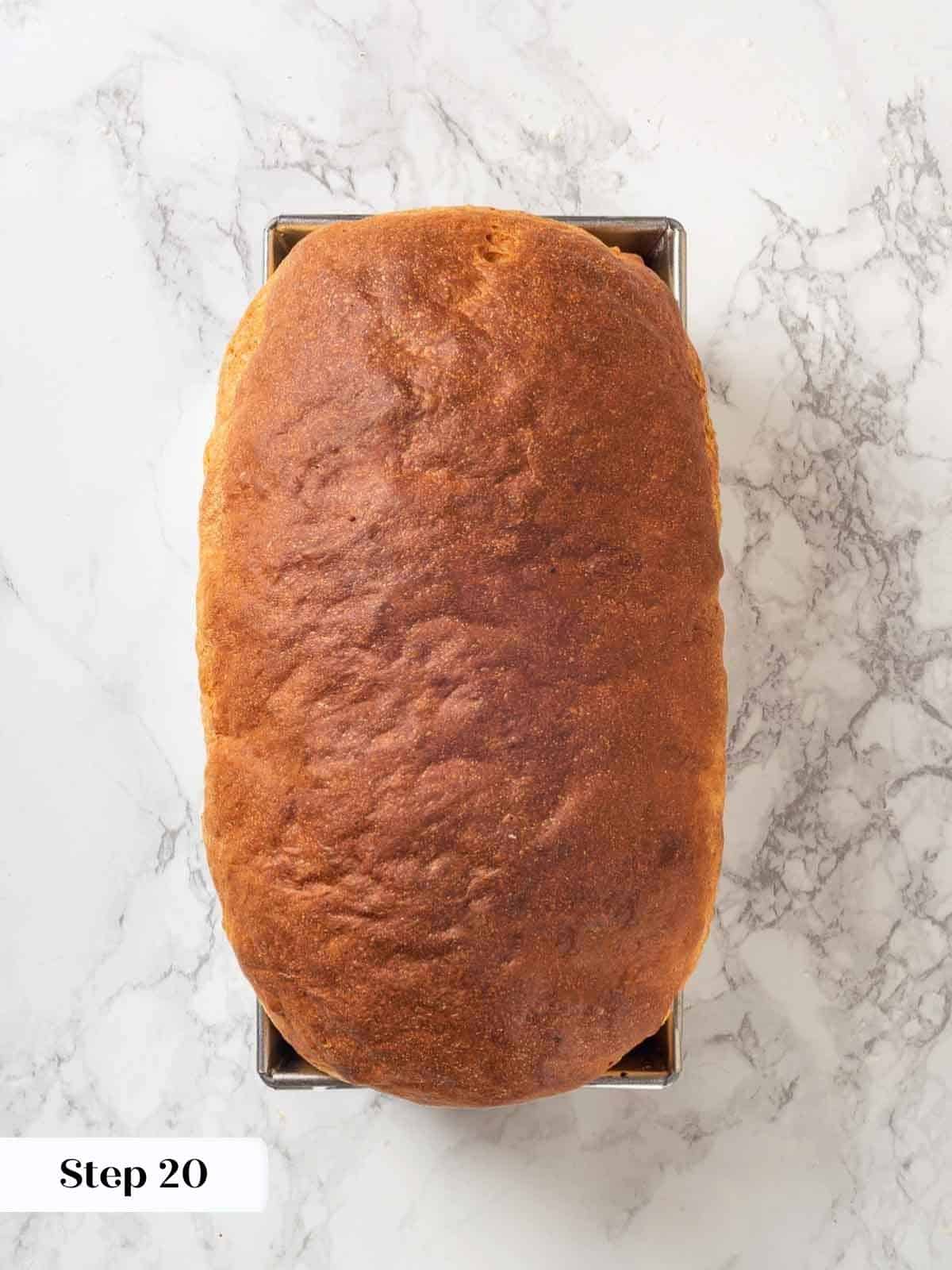 A fully baked loaf of potato bread in a metal loaf pan, golden and fluffy.