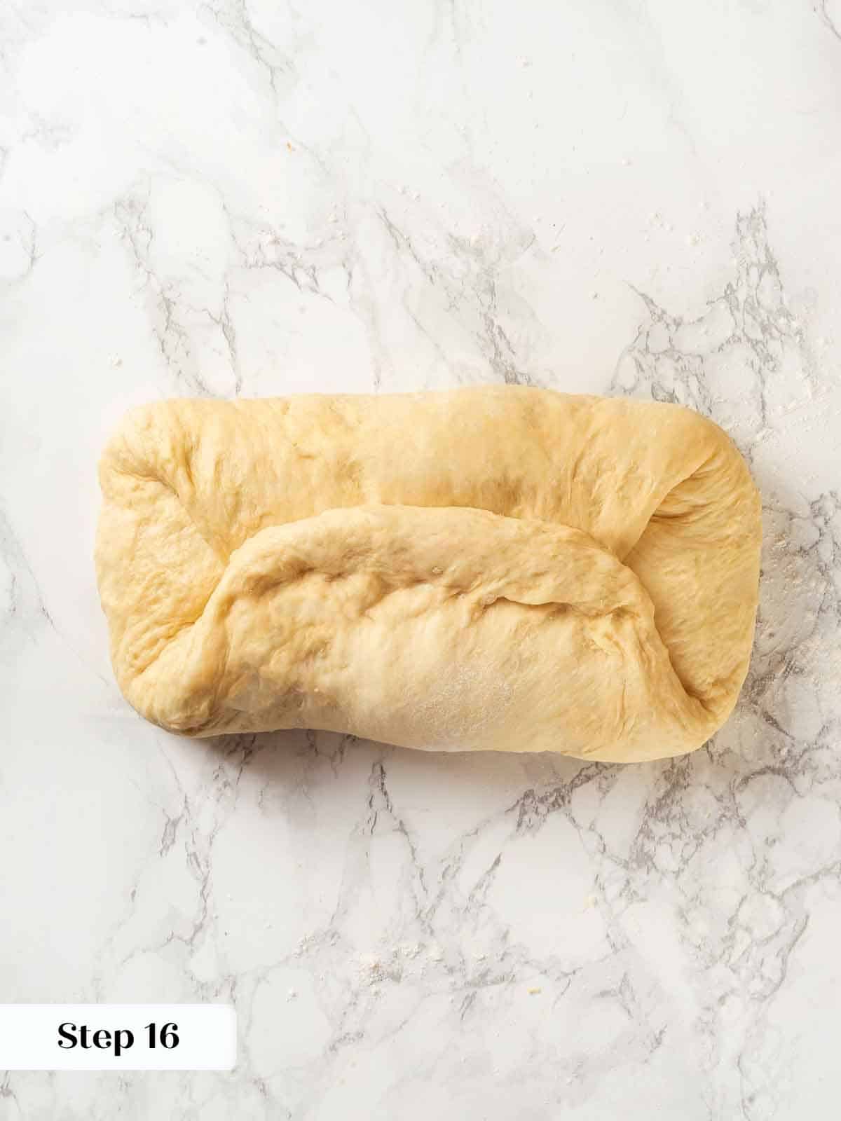 A baker demonstrating repeated folds in potato bread dough for strength.