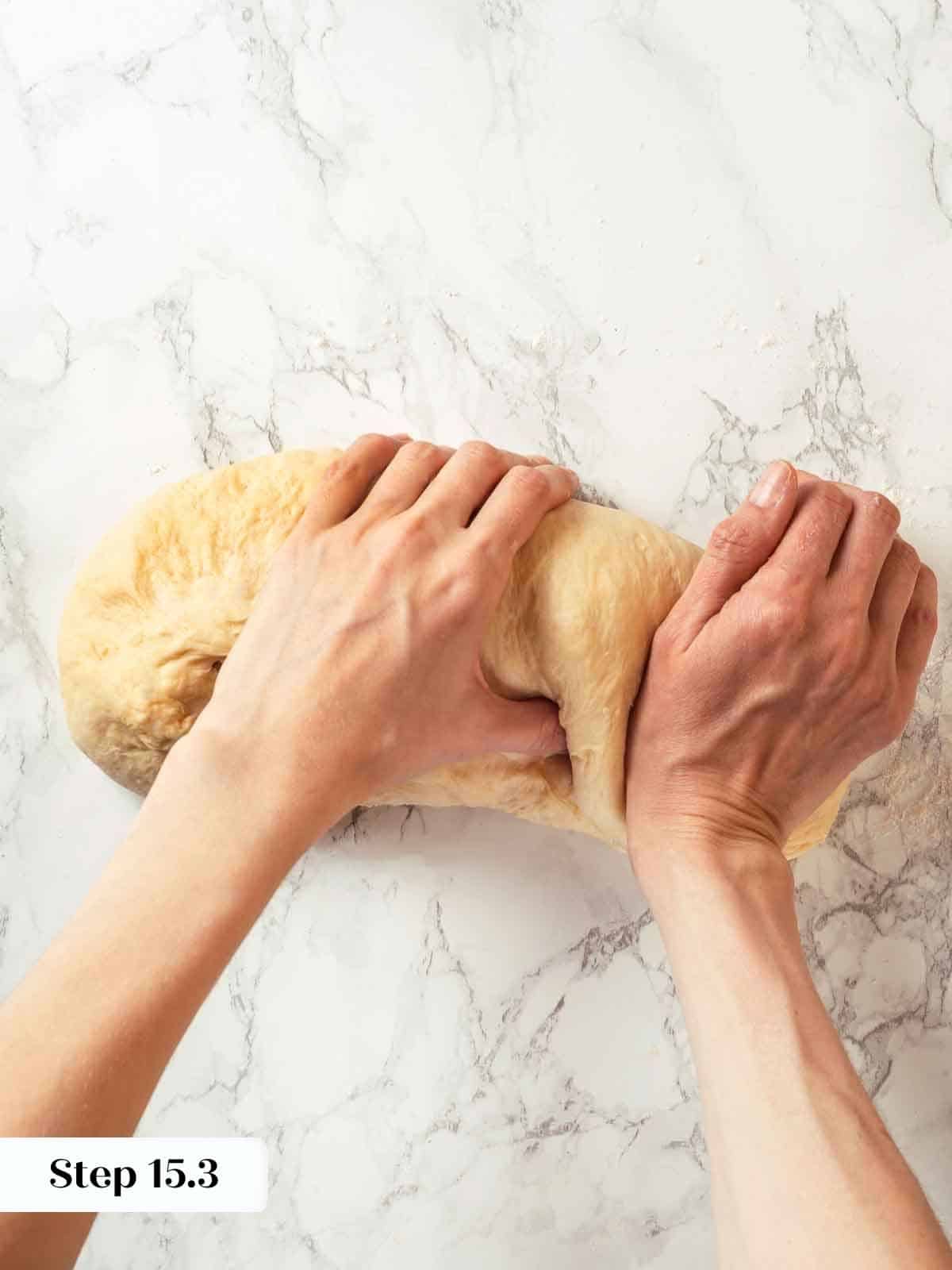 Hands pressing and sealing the edge of the potato bread dough to create a tight seam.