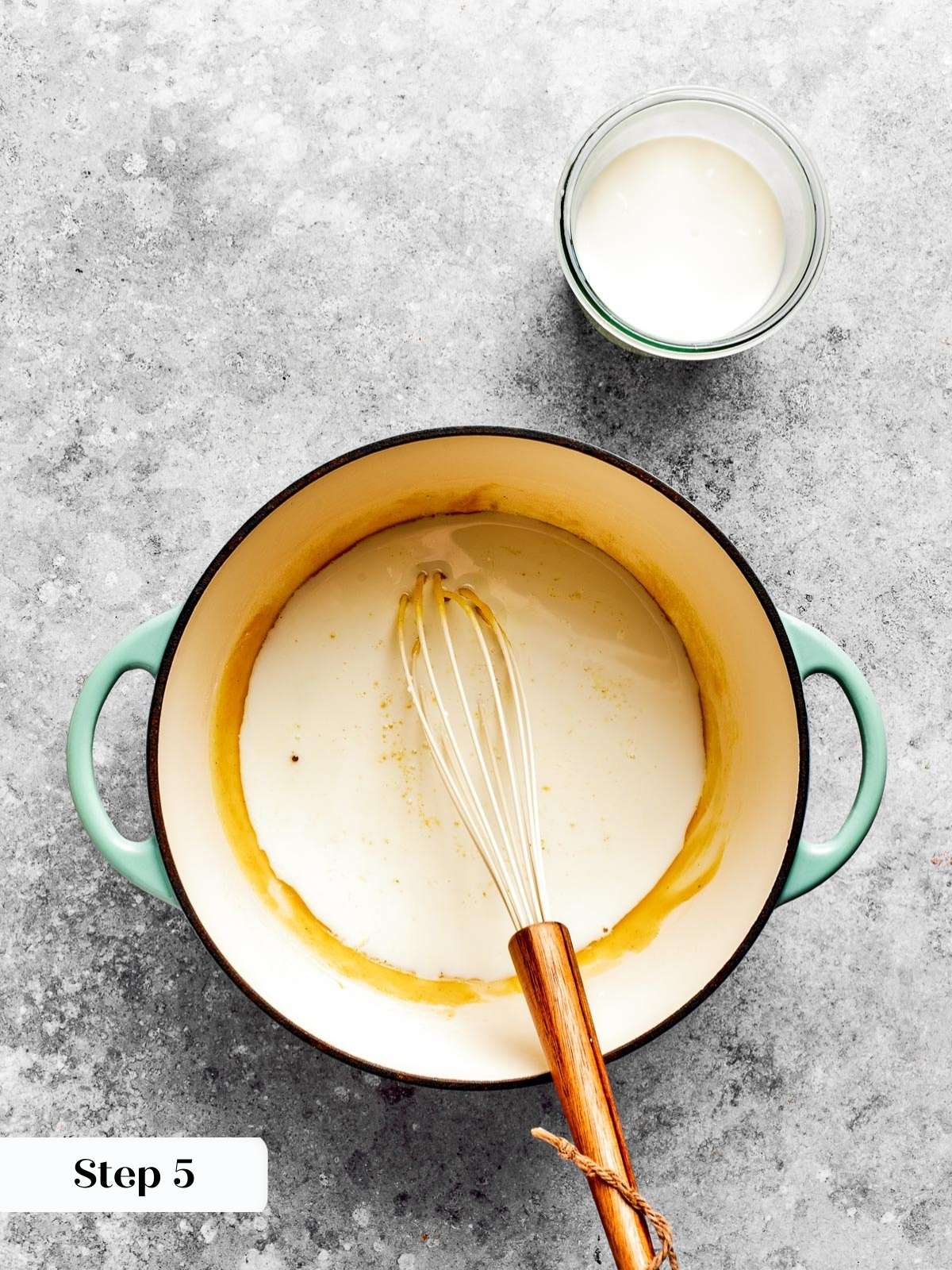 Milk being added slowly to a thickened roux for a smooth sauce.