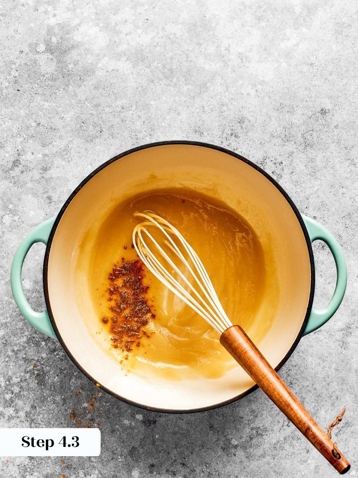 A whisk mixing flour in a saucepan over low heat.