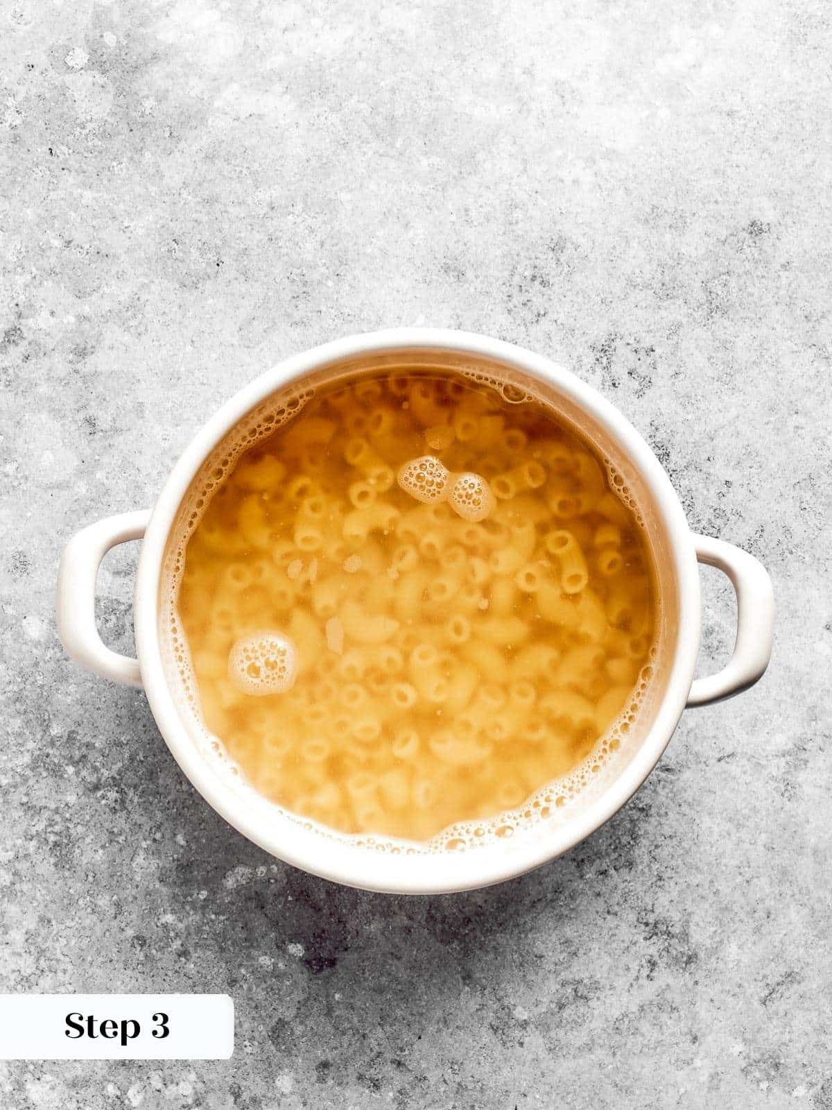 A pot of boiling water with macaroni cooking inside.
