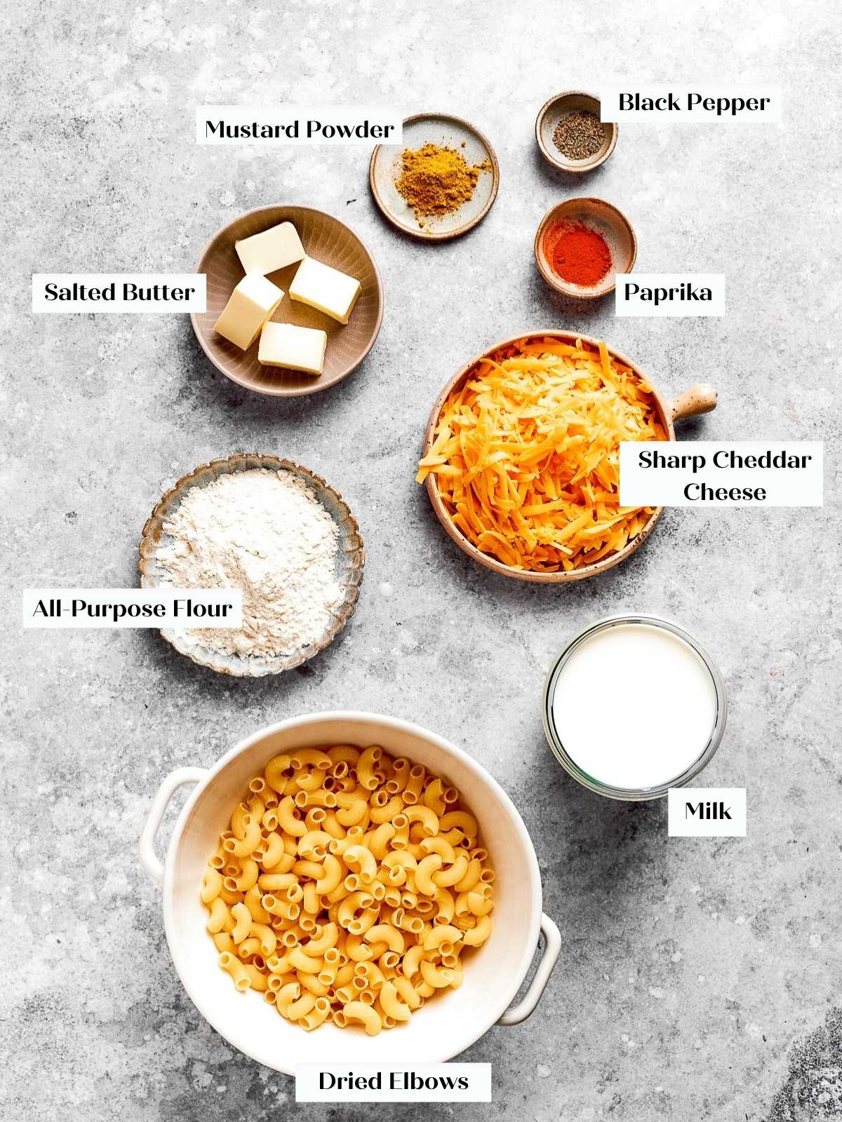 All the ingredients for baked mac and cheese spread out on a countertop.