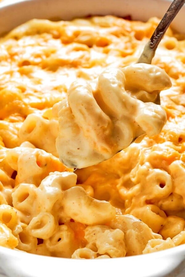 A large spoon lifting a creamy, cheesy scoop of baked mac and cheese.