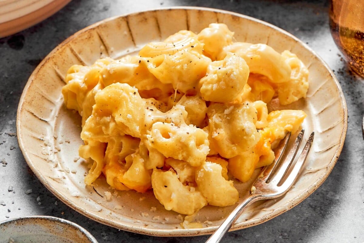 A serving of mac and cheese being plated straight from the oven.