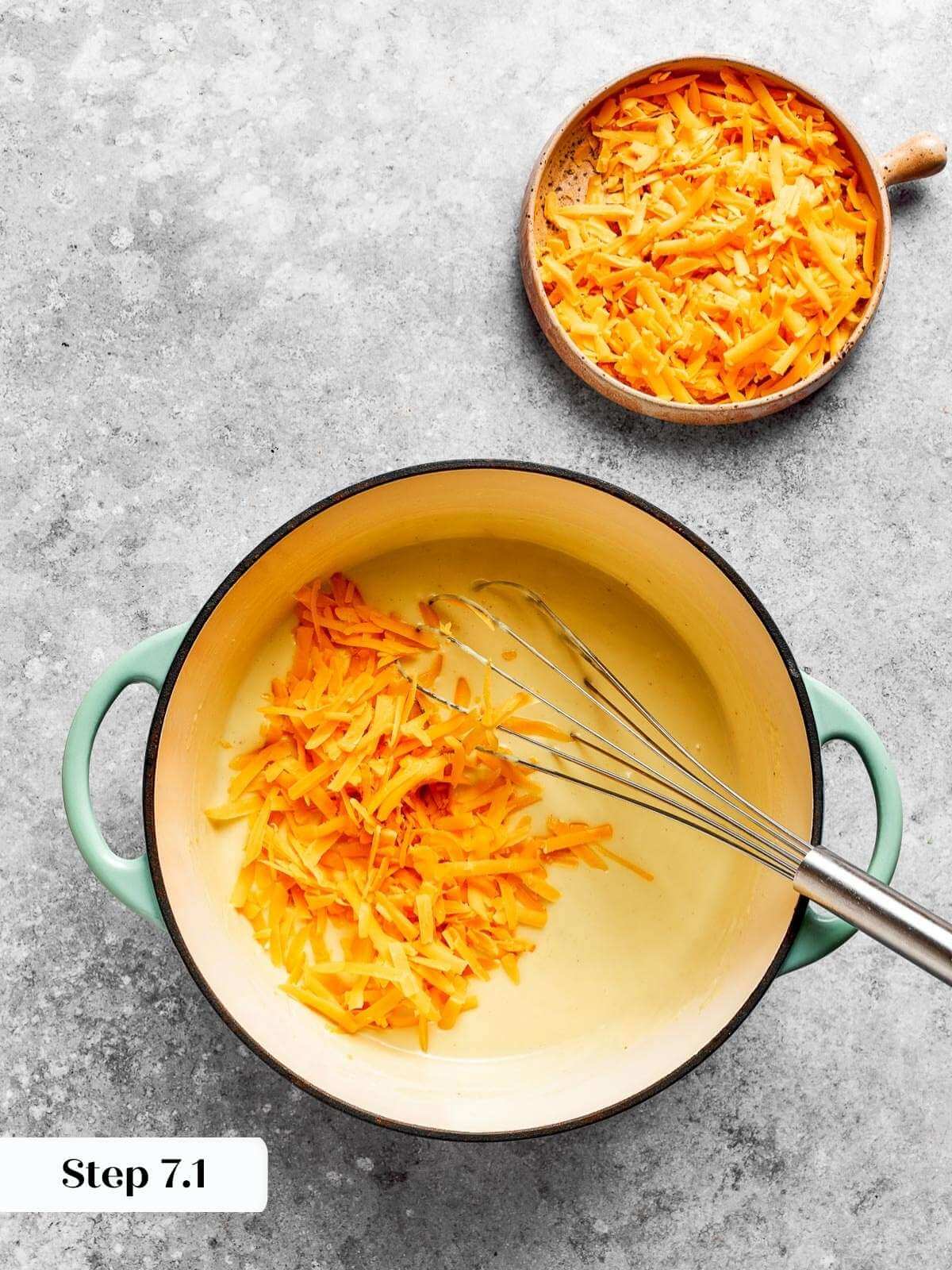 Shredded cheddar melting into the thickened roux.