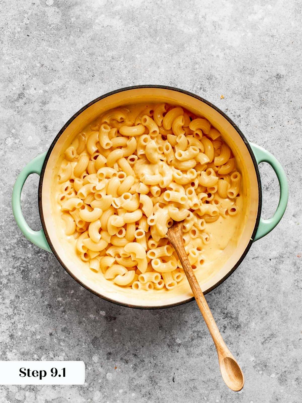 Pasta being mixed into a creamy cheese sauce.
