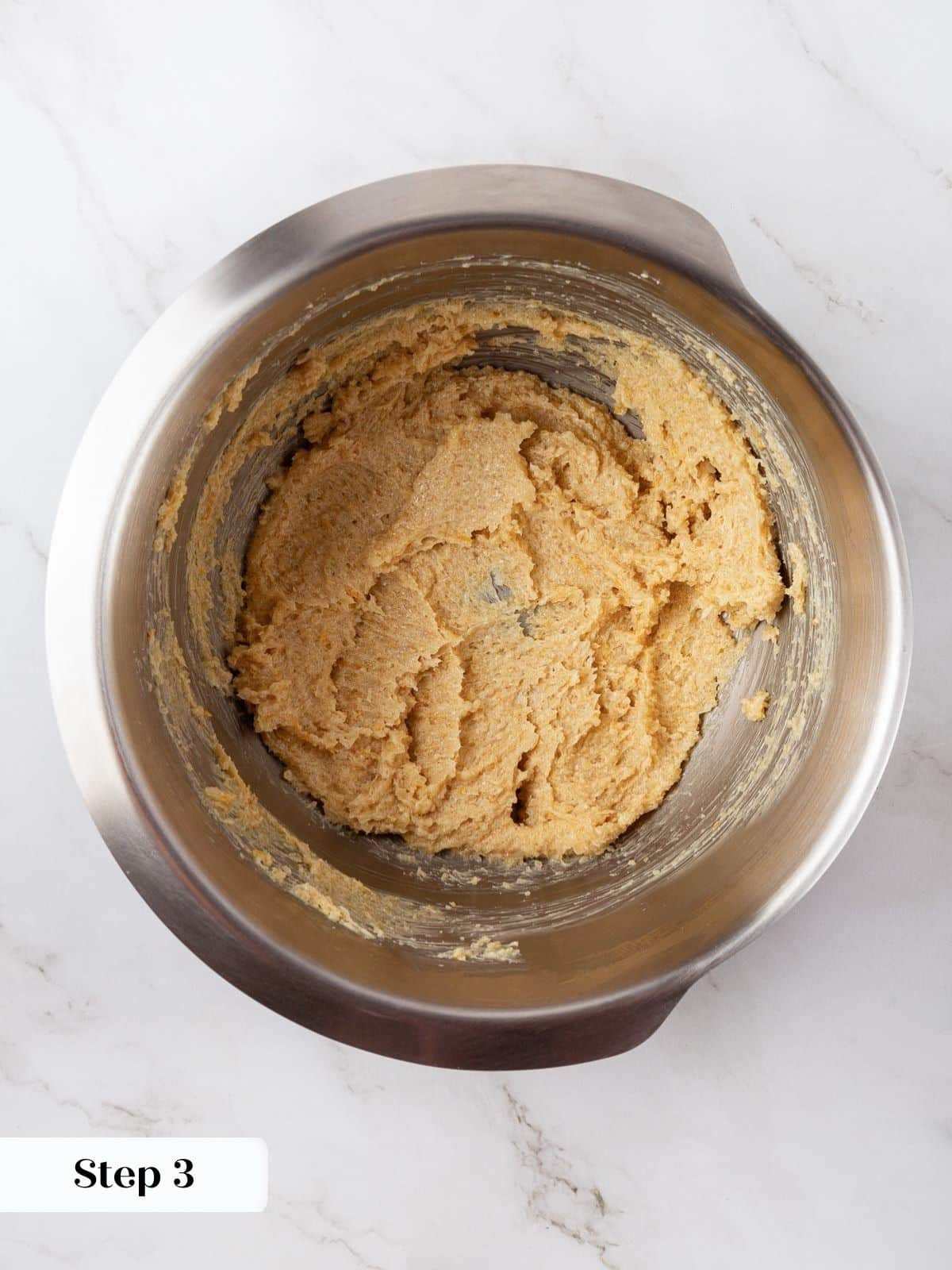 Softened butter and sugar being creamed together in a mixing bowl.