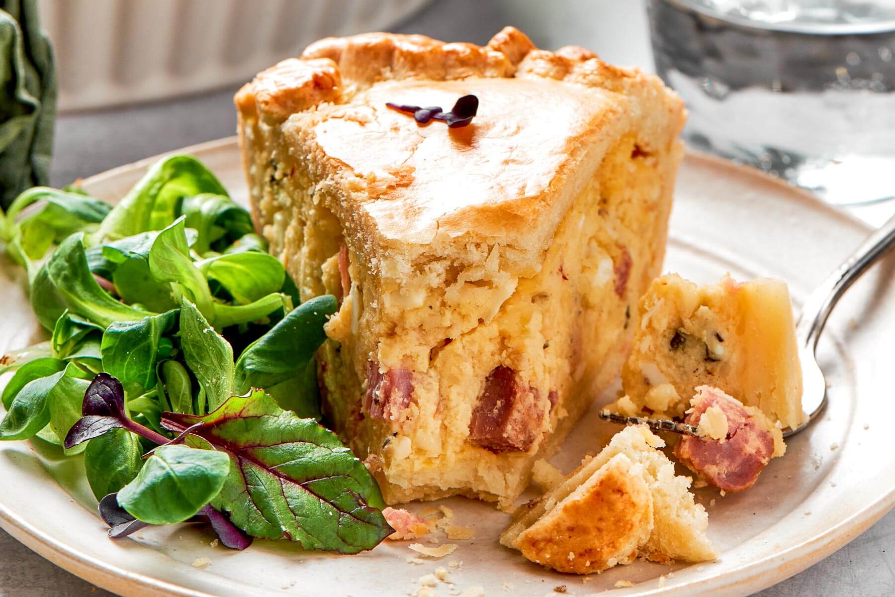 A slice of pizza rustica with a bite taken out, showing its soft, cheesy interior.