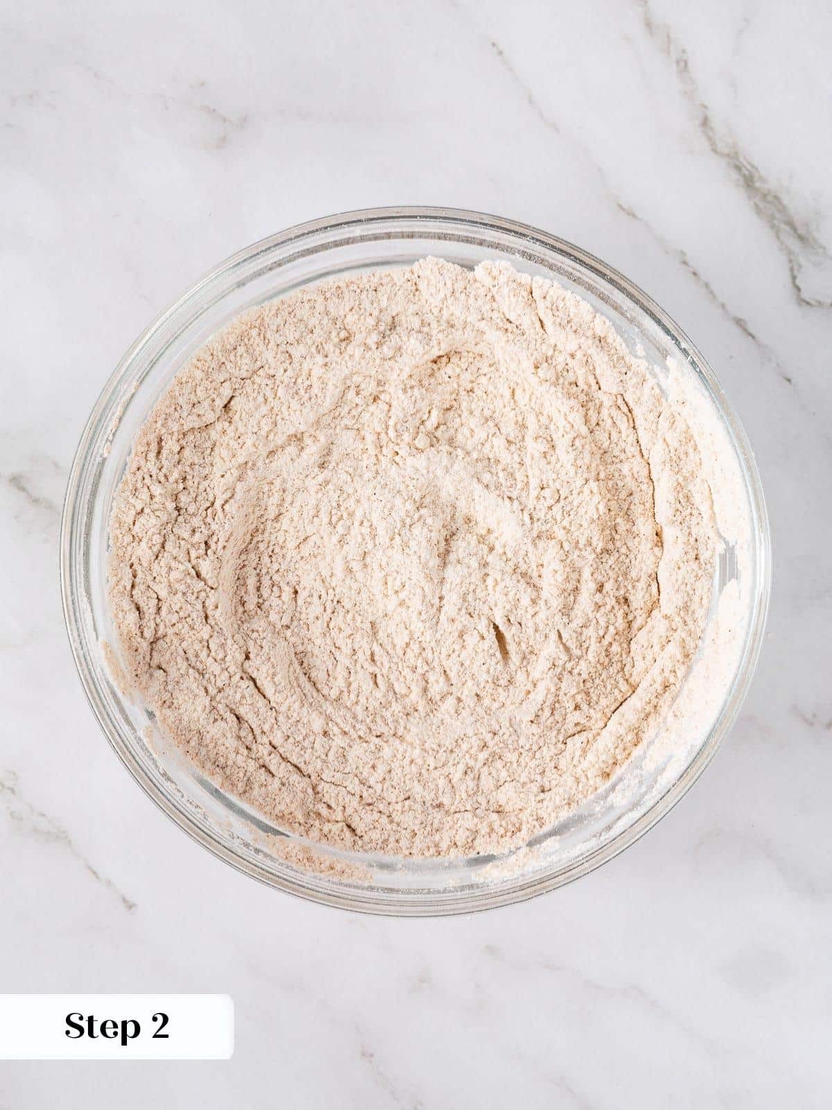 Dry ingredients like flour and spices whisked in a bowl.