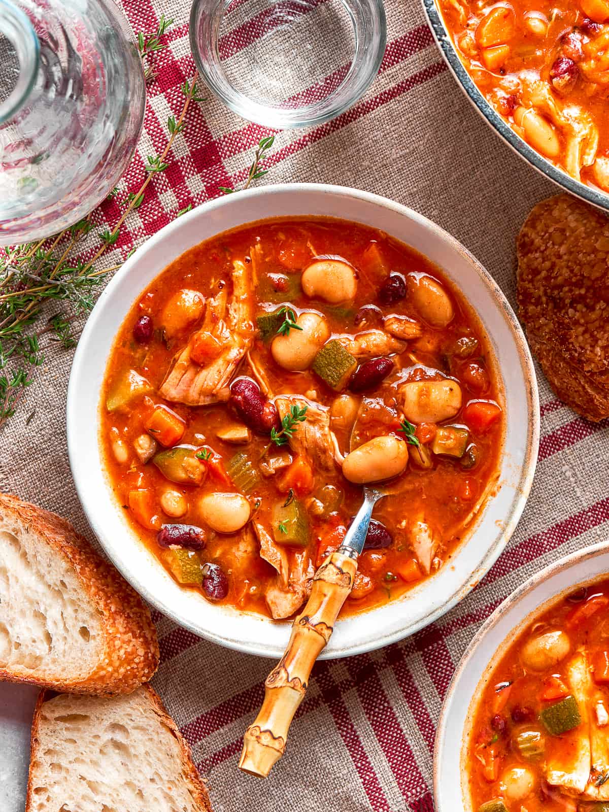 A spoonful of chicken and vegetables from soup bowl.