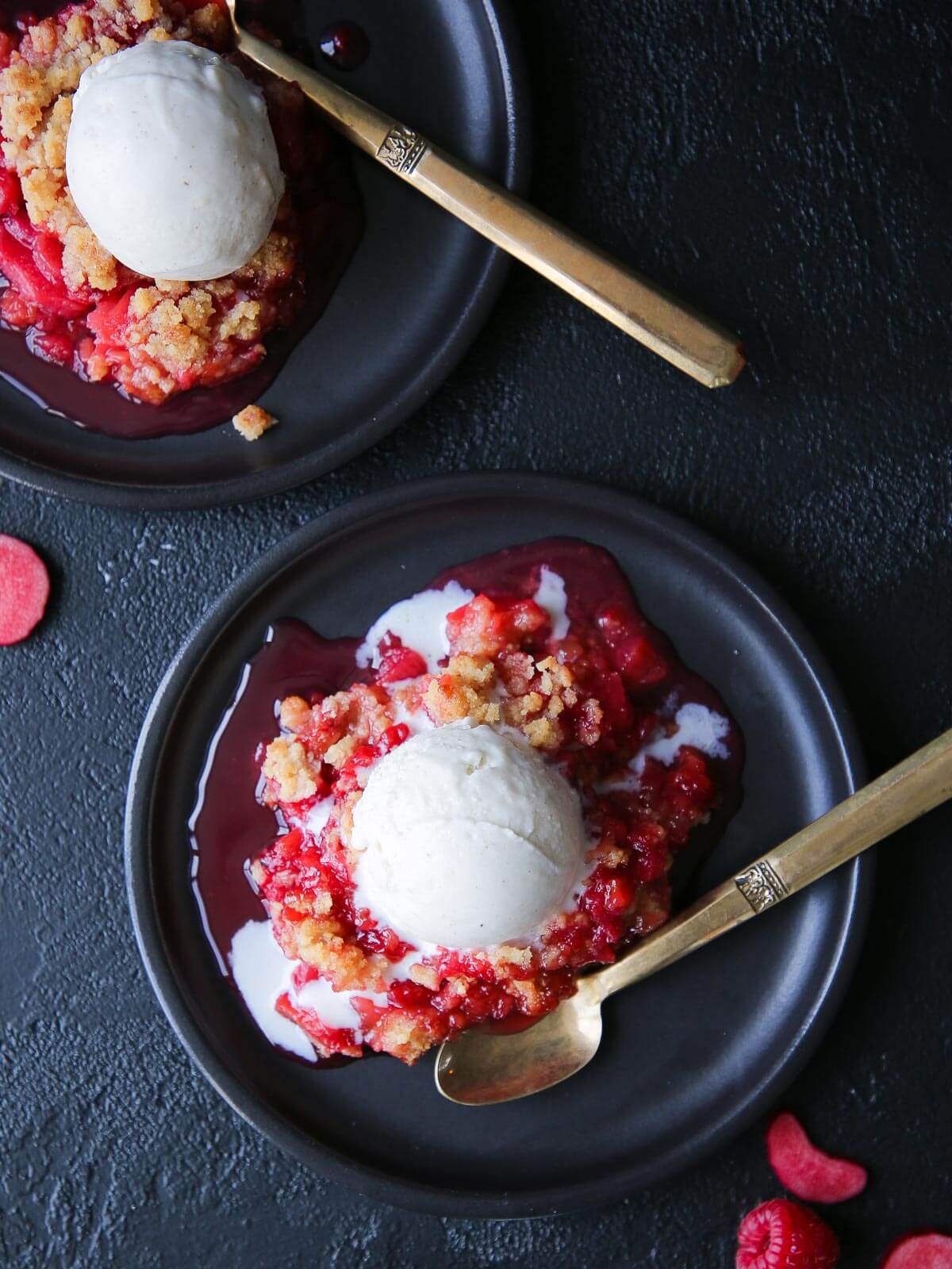 Fresh raspberries scattered near a served portion of crisp.
